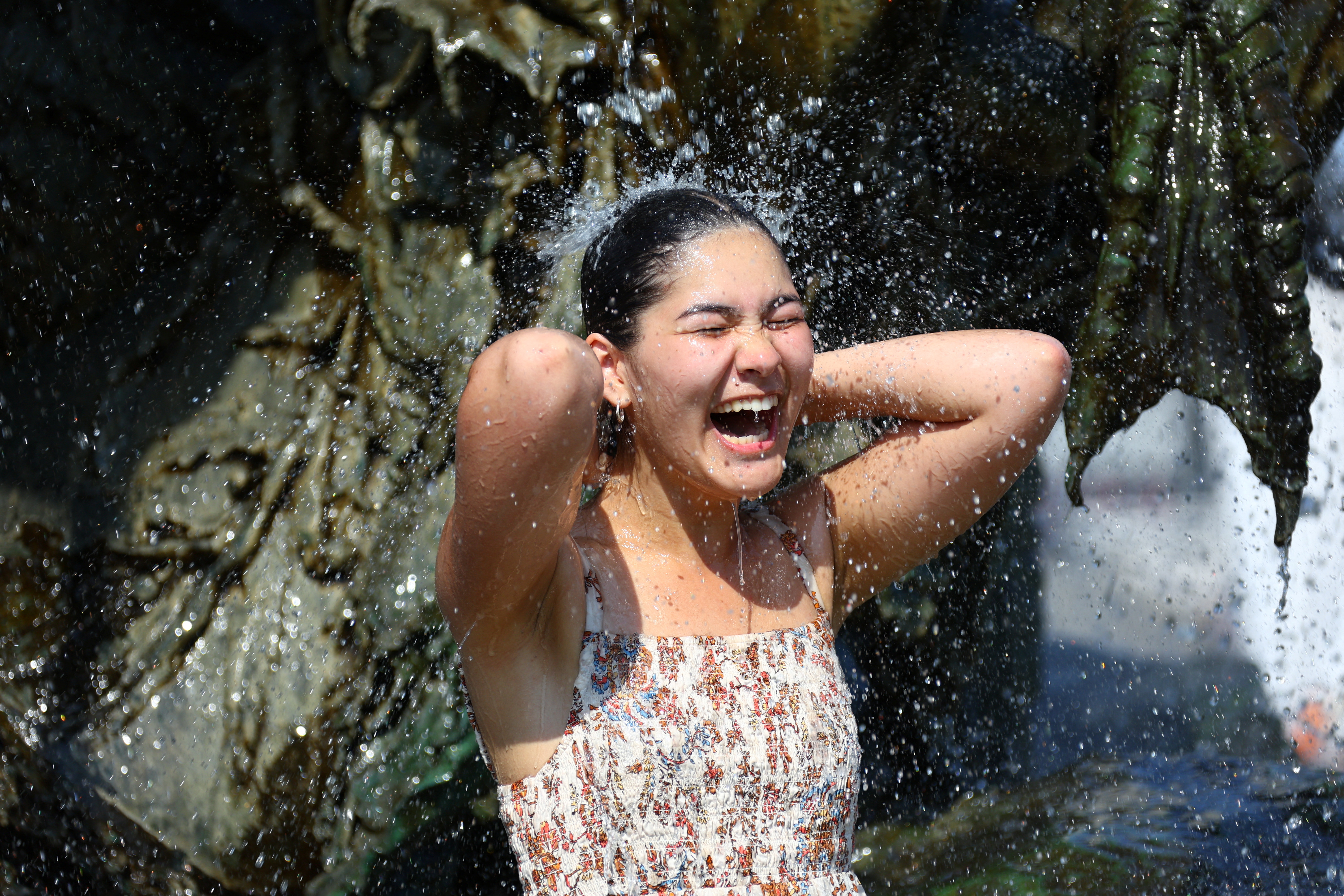 La turista canadese Sophia, 20 anni, si rinfresca nella Fontana del Nettuno nel centro di Berlino.