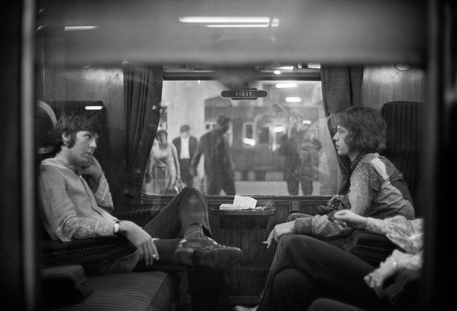 25 de agosto de 1967: Paul McCartney de los Beatles y Mick Jagger de los Rolling Stones se sientan uno frente al otro en un tren en la estación de Euston, esperando la salida a Bangor. (Foto de Victor Blackman/Express/Getty Images)
