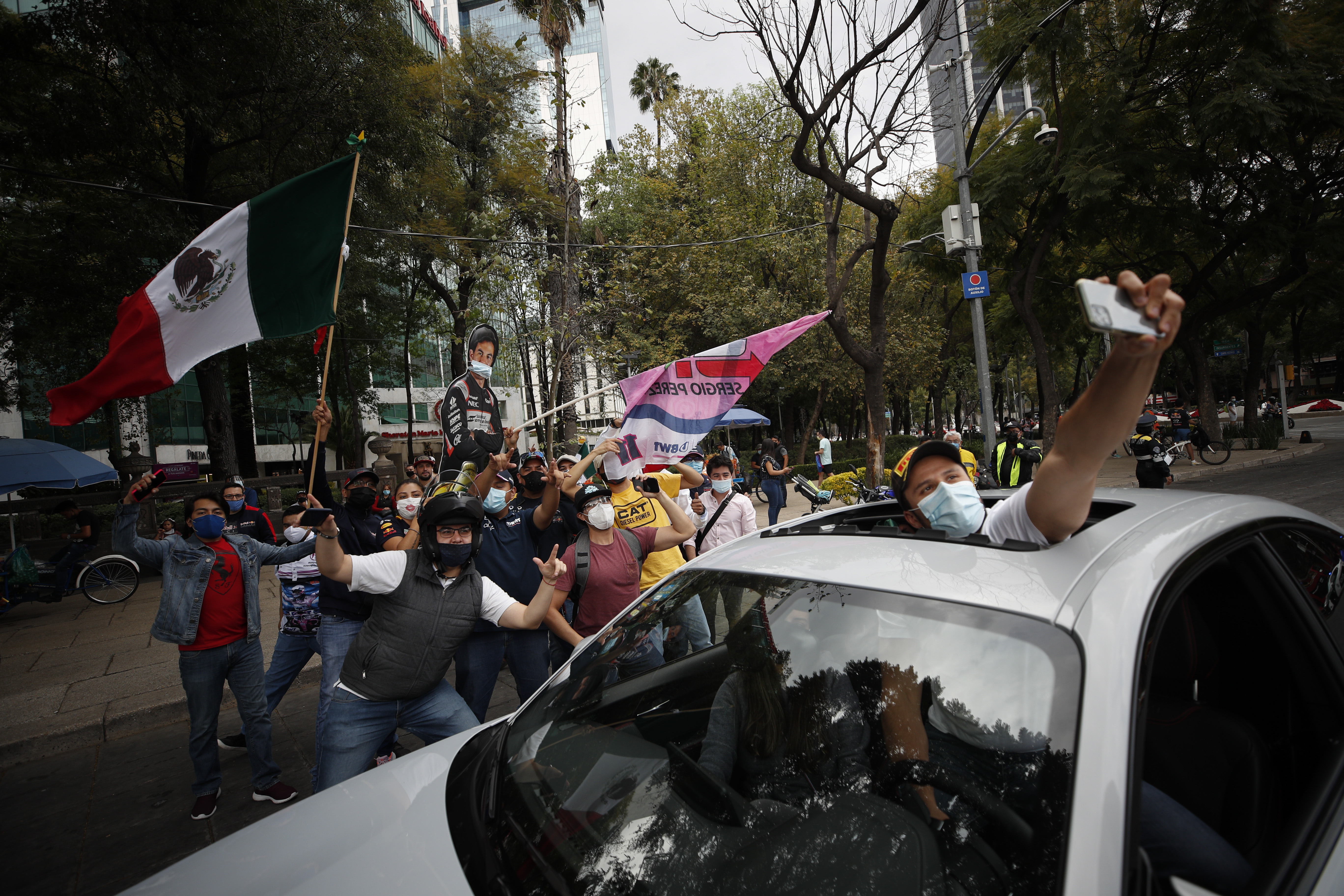 Un fan que pasa en un automóvil se detiene para posar para una foto con personas que celebran la primera victoria de Sergio