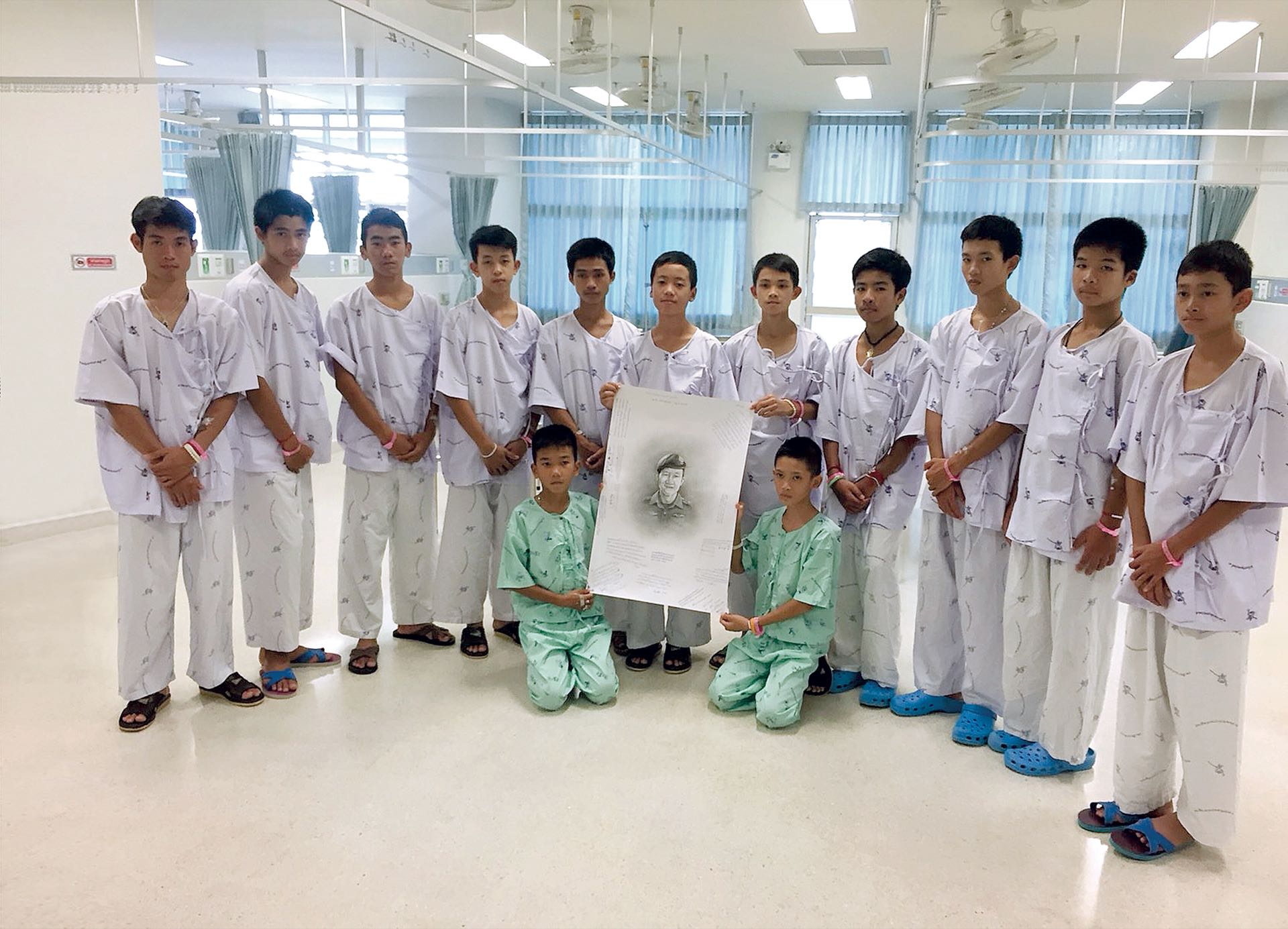 Los 12 niños y el entrenador rescatados en Tailandia en el Hospital Chiang Rai Prachanukroh, donde pasaron una cuarentena luego del encierro, rindieron tributo al buzo fallecido durante el operativo (AFP)