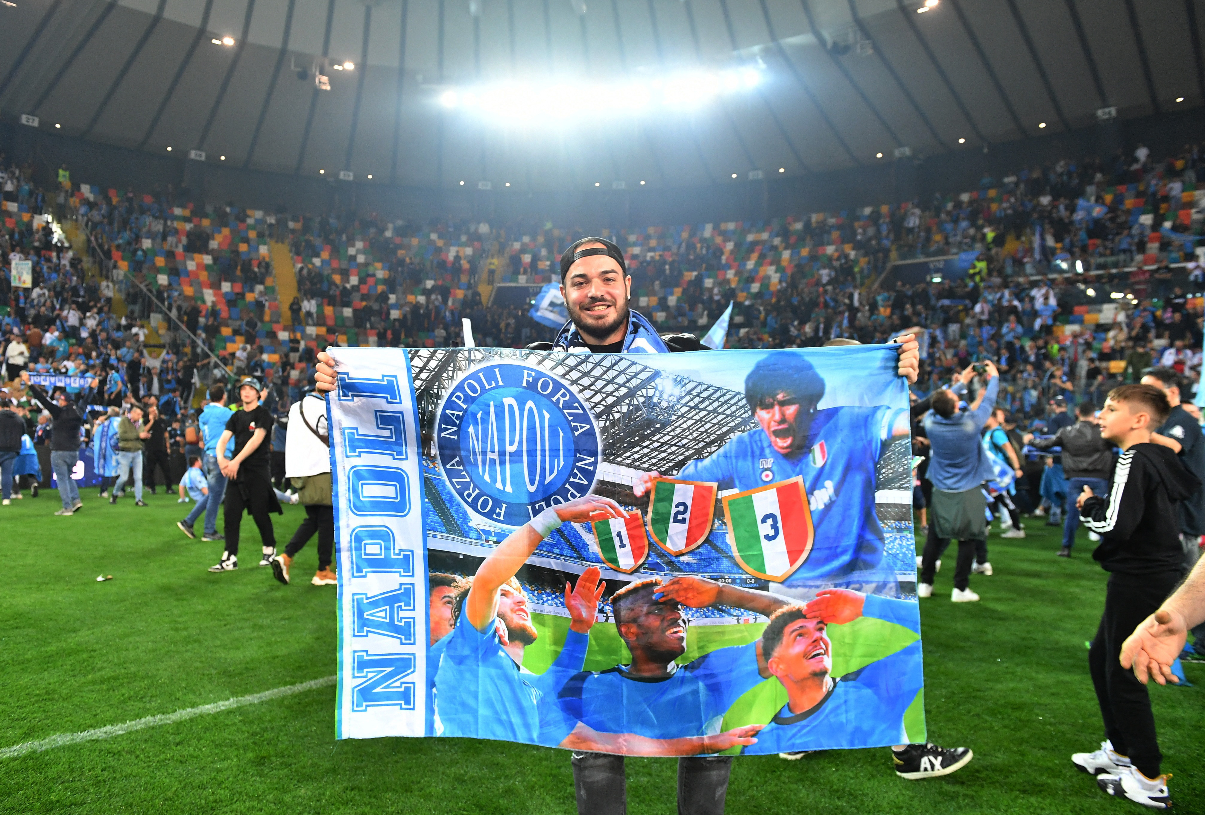 Original montaje en la bandera con tres jugadores actuales que observan hacia el cielo y aparece Diego Maradona 