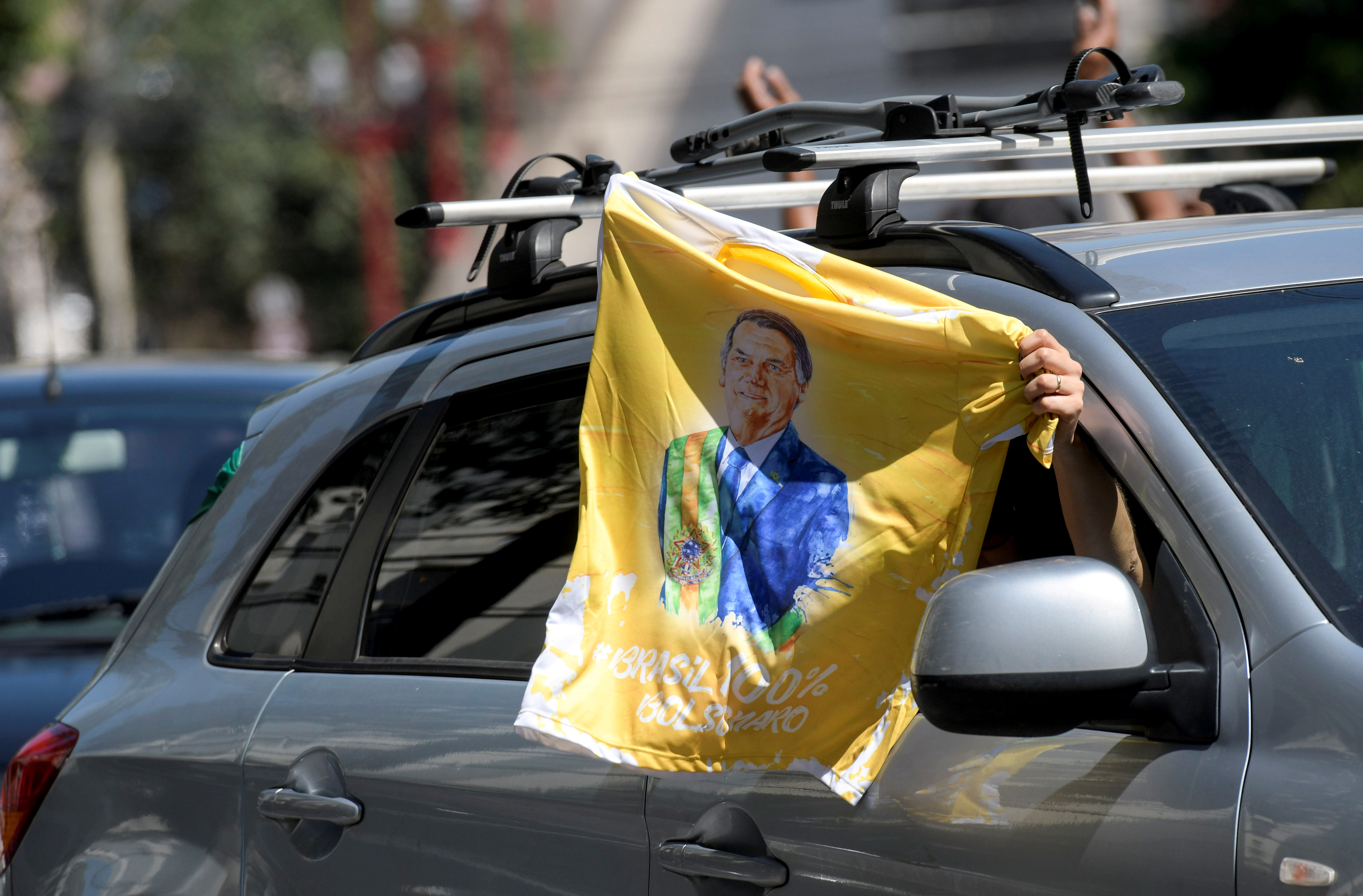 Un manifestante flamea una bandera con la cara del presidente de Brasil, Jair Bolsonaro, durante una protesta contra las restricciones por el coronavirus en Brasilia (REUTERS/Washington Alves)