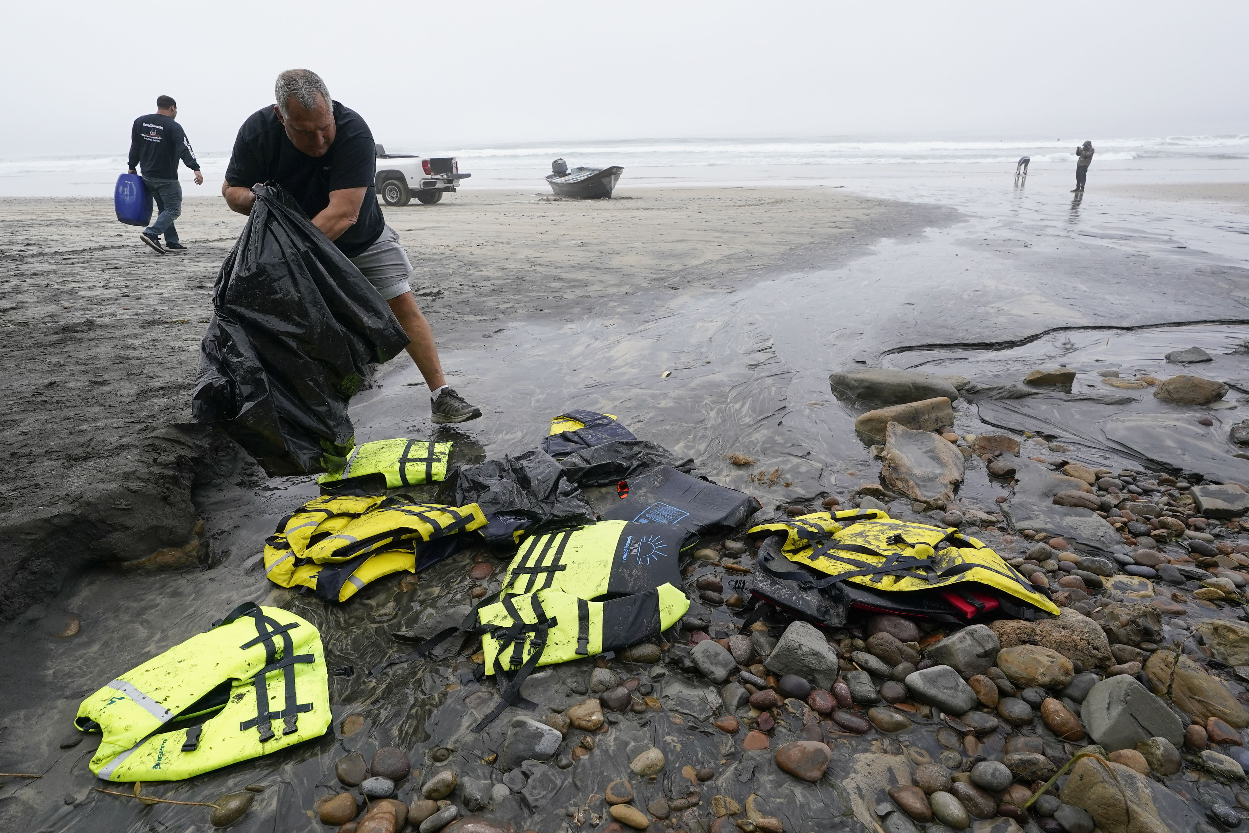 ARCHIVE - March 12, 2023, in front of Black's Beach on the coast of San Diego, recovering life jacket bags found around one of two boats that capsized while transporting people Rescuer Robert Butler.  (AP Photo/Gregory Bull, Archivo)