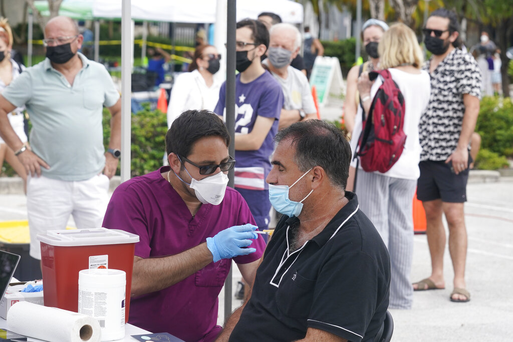 Carlos Anacleto cierra los ojos mientras recibe la vacuna COVID-19 de Pfizer de manos del enfermero Jorge Tase, mientras otros esperan su turno, el miércoles 4 de agosto de 2021, en Miami Beach, Florida (Ap)