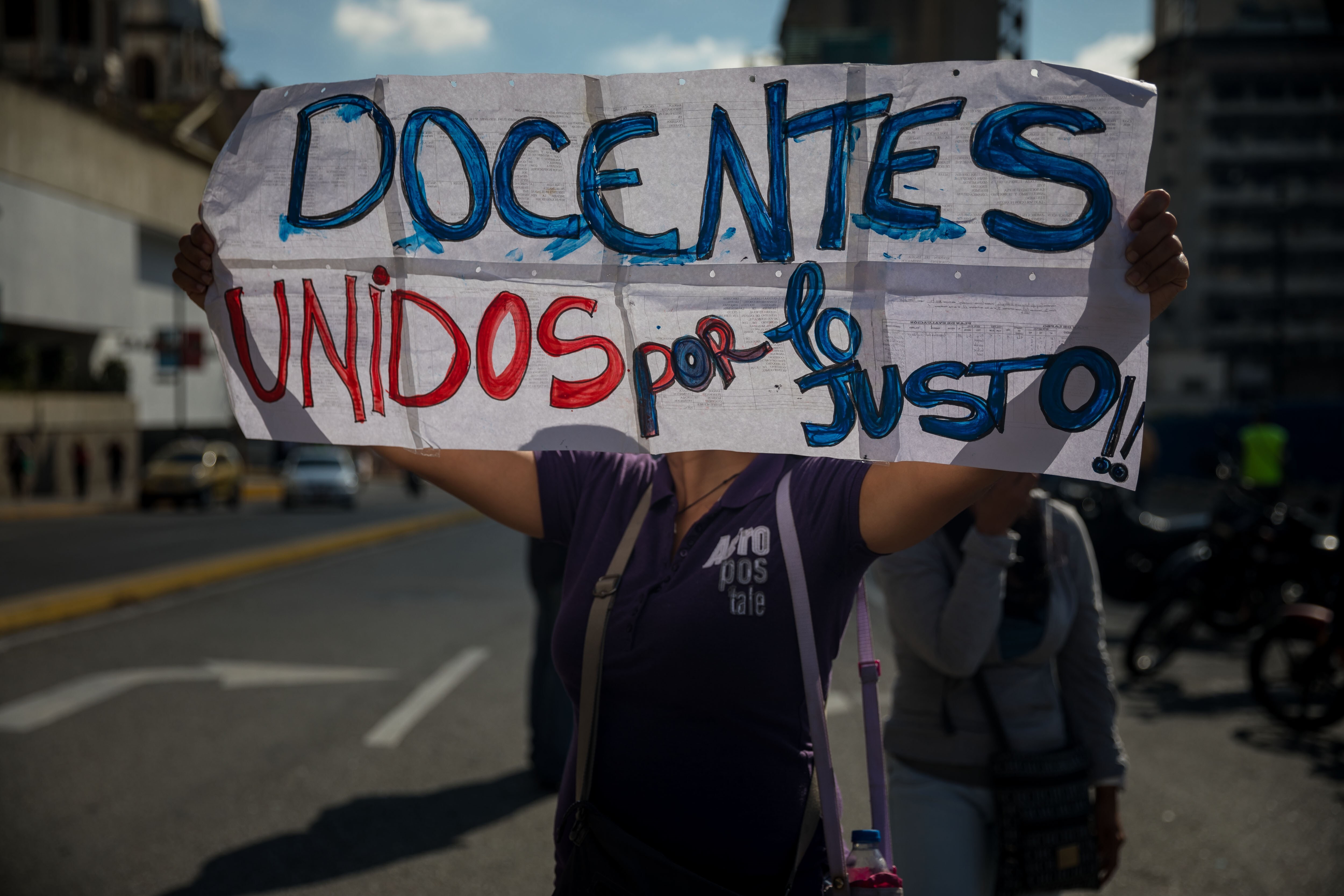 Una mujer sostiene un cartel durante una manifestación de profesores, frente al edificio del Ministerio de educación en Caracas (Venezuela), en un una fotografía de archivo. EFE/ Miguel Gutiérrez
