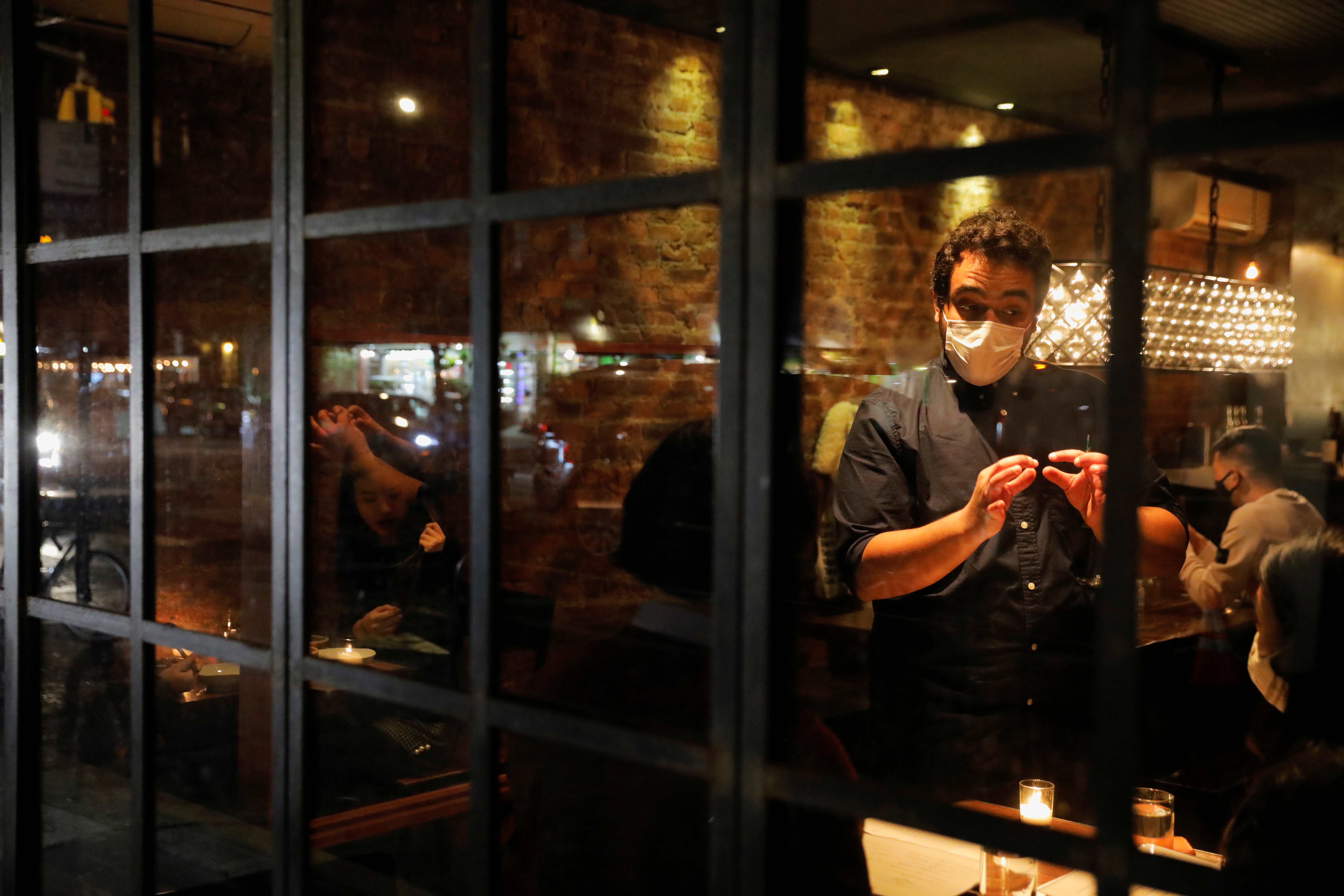 A person serves customers at Oiji, a restaurant in the East Village as new restrictions were announced on bars and restaurants for 10 PM closure, to help fight the spread of the coronavirus disease (COVID-19), in Manhattan, New York City November 13, 2020. REUTERS/Andrew Kelly