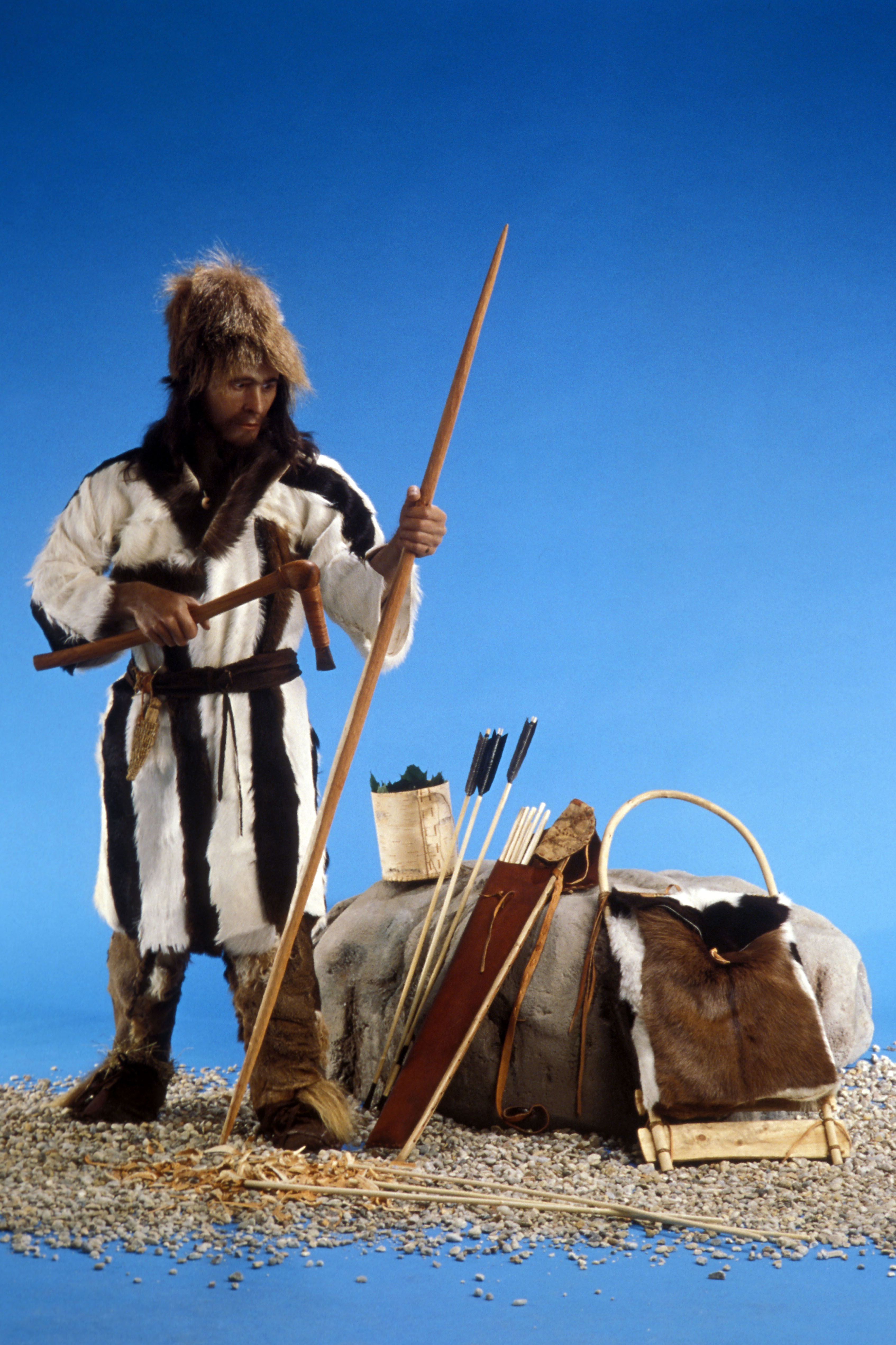 La versión terminada de Ötzi, el hombre de hielo, con un gorro de piel de oso, abrigo y polainas de piel de cabra y sandalias de cuero llenas de paja. Llevaba un cuchillo de pedernal en el cinturón y se le representa con su hacha de bronce y un arco (Patrick Landmann/Getty Images)