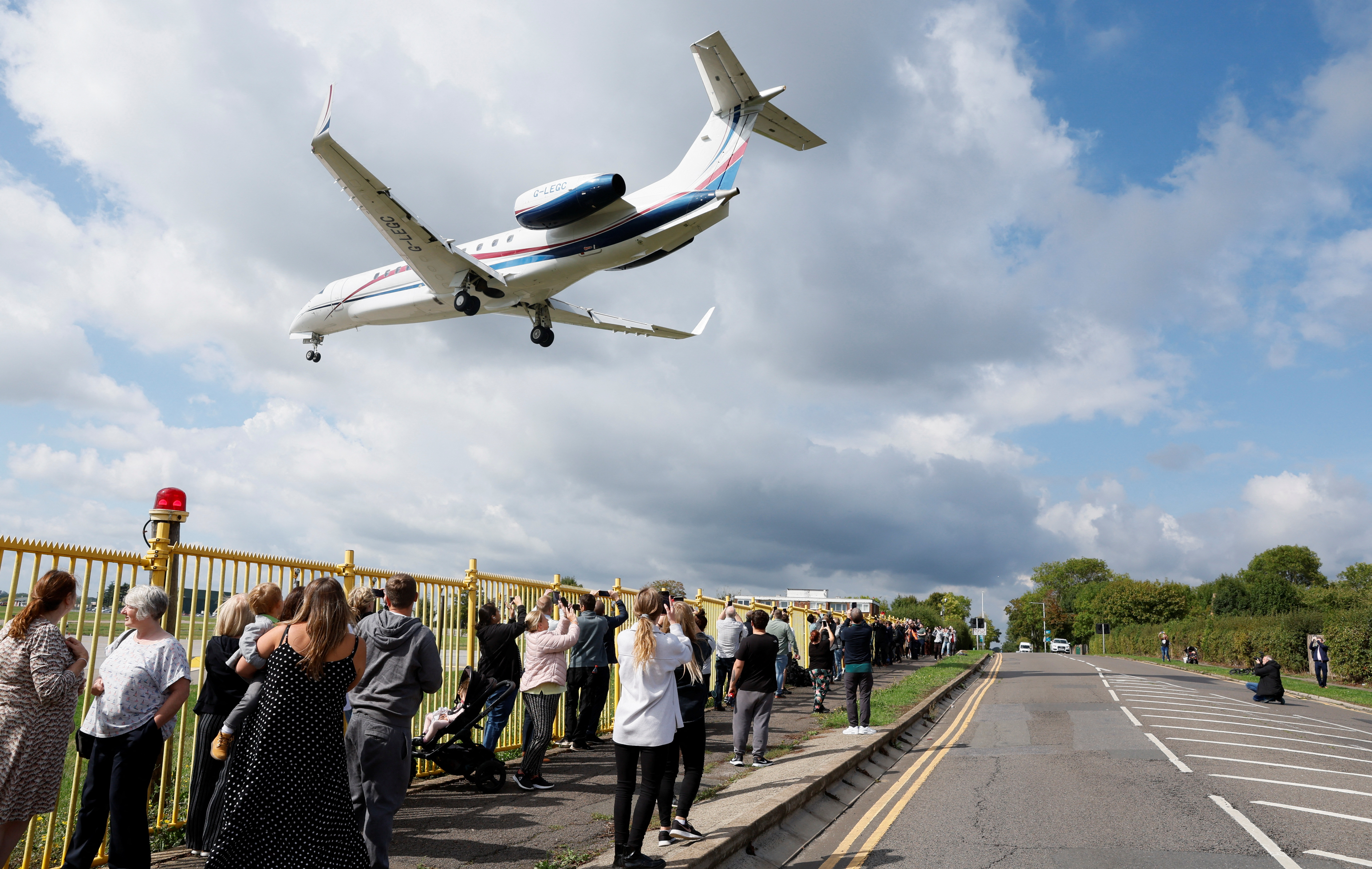 El avión en el que viajaba el rey Carlos III aterriza en Londres mientras que un grupo de personas toman fotos de su llegada 
