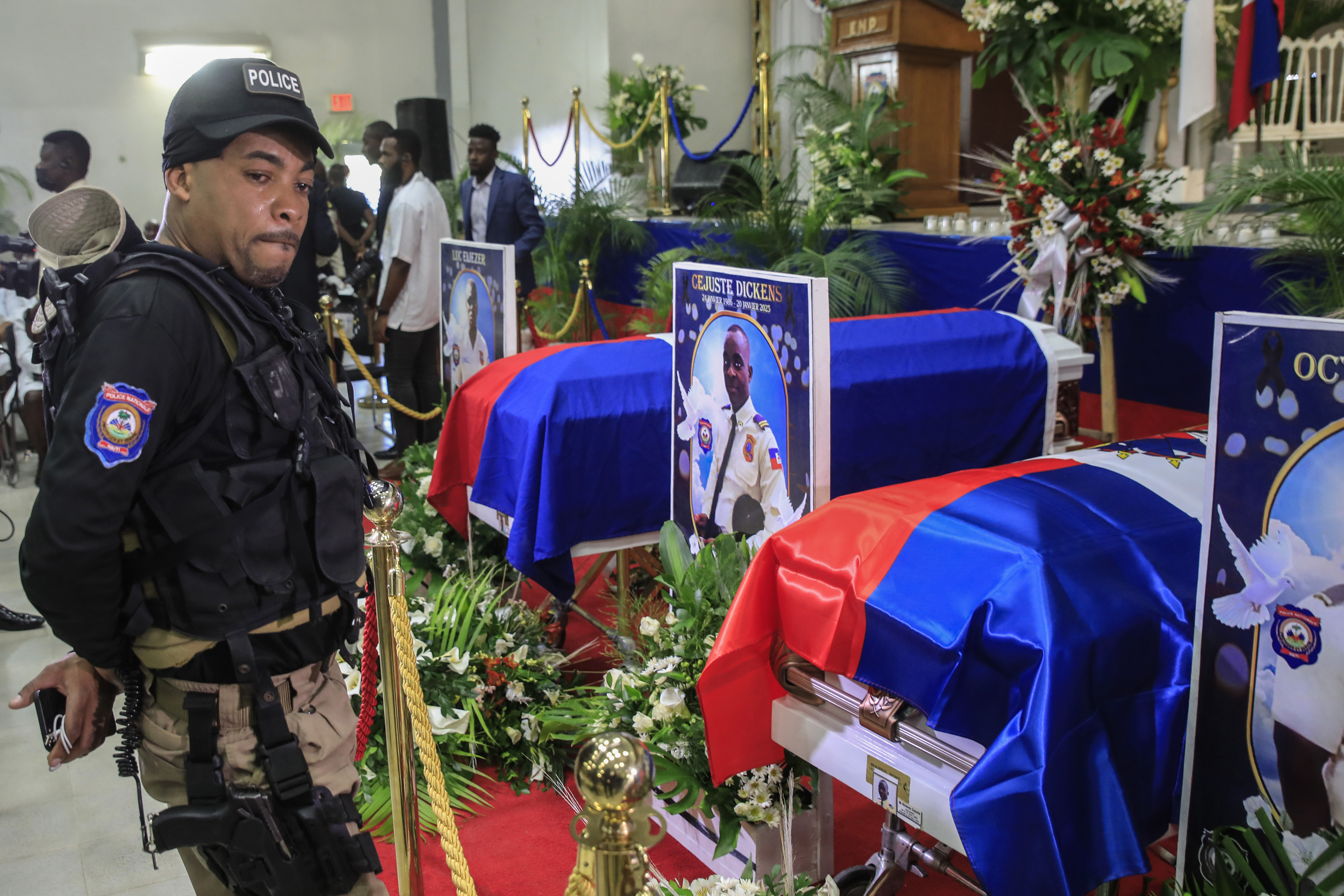A policeman weeps next to the coffins of the three officers killed on the job, at the Police Academy in Port-au-Prince, Haiti, on January 31, 2023. The policemen were killed in a gang ambush on January 20 in the capital.  (AP Photo/Odelyn Joseph)