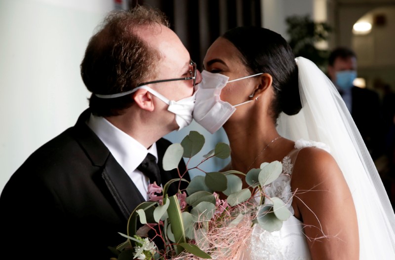 Los recién casados Diego Fernandes, de 46 años, y Deni Salgado, de 30, se besan con máscaras protectoras en una ceremonia de boda con solo testigos y sin invitados, ya que las reuniones públicas están prohibidas como parte de las medidas de bloqueo de Italia para prevenir la propagación de la enfermedad por coronavirus (COVID-19) en Nápoles, Italia. 20 de marzo de 2020. REUTERS/Ciro De Luca