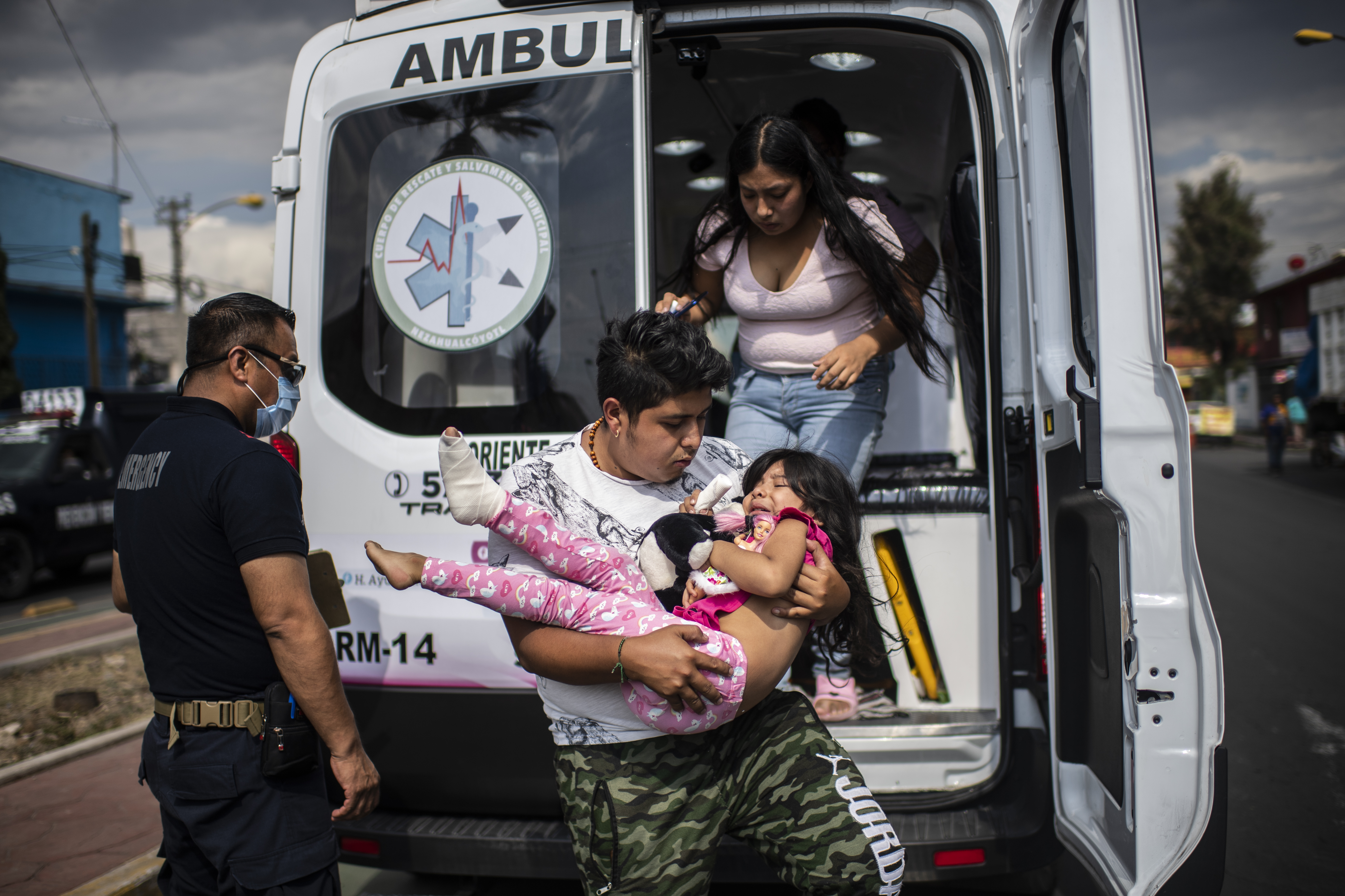 El paramédico Sergio Villafan observa cómo un hombre lleva a una niña herida en un accidente de bicicleta en Ciudad Nezahualcóyotl, Estado de México, México, el 18 de junio de 2020 durante la nueva pandemia de coronavirus de COVID-19. (Foto por Pedro PARDO / AFP)