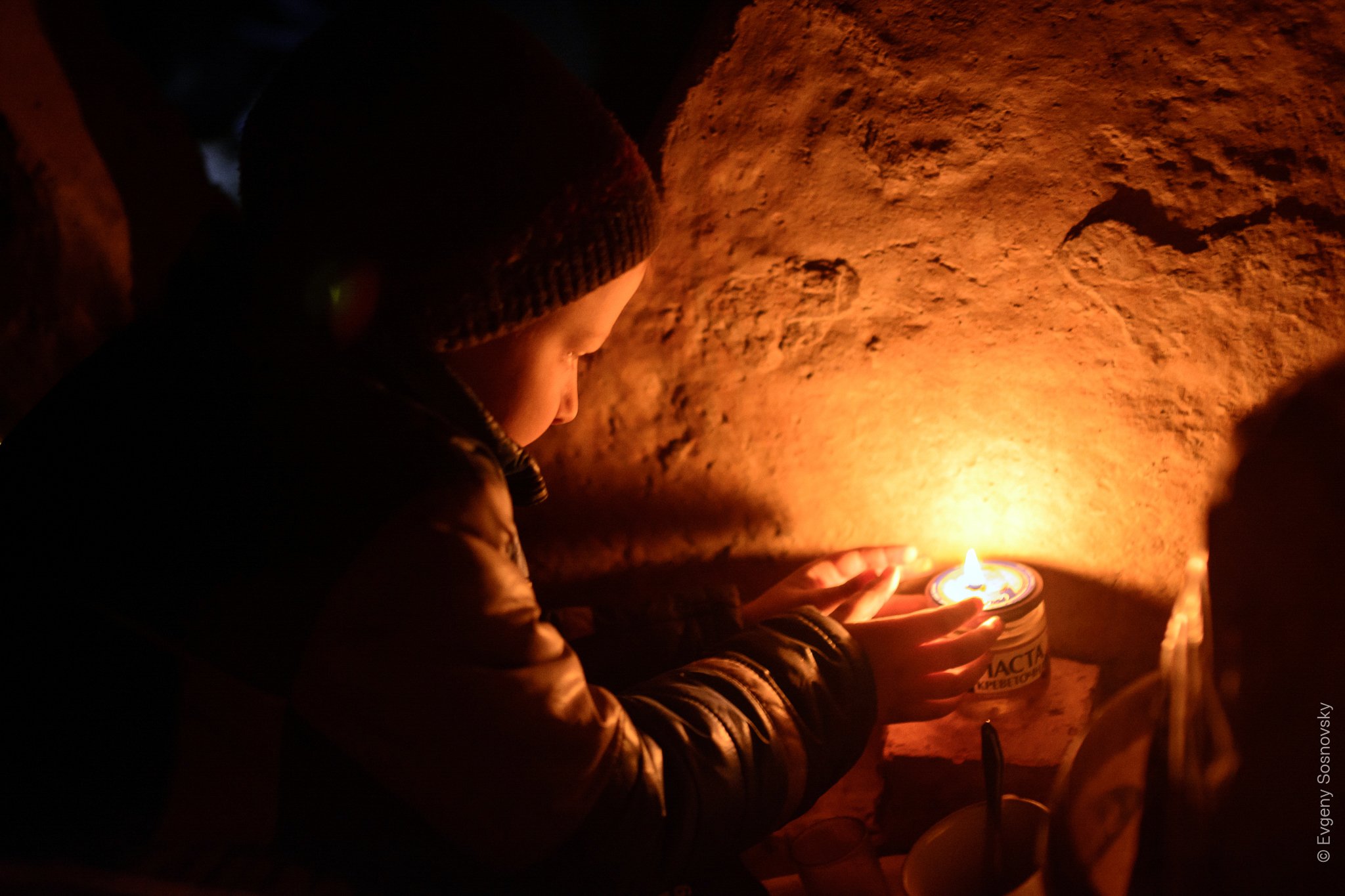 Yehorka, de 8 años, prende una vela en el refugio que compartió con su familia y donde escribió un diario de guerra. (Evgeny Sosnovsky/Facebook)