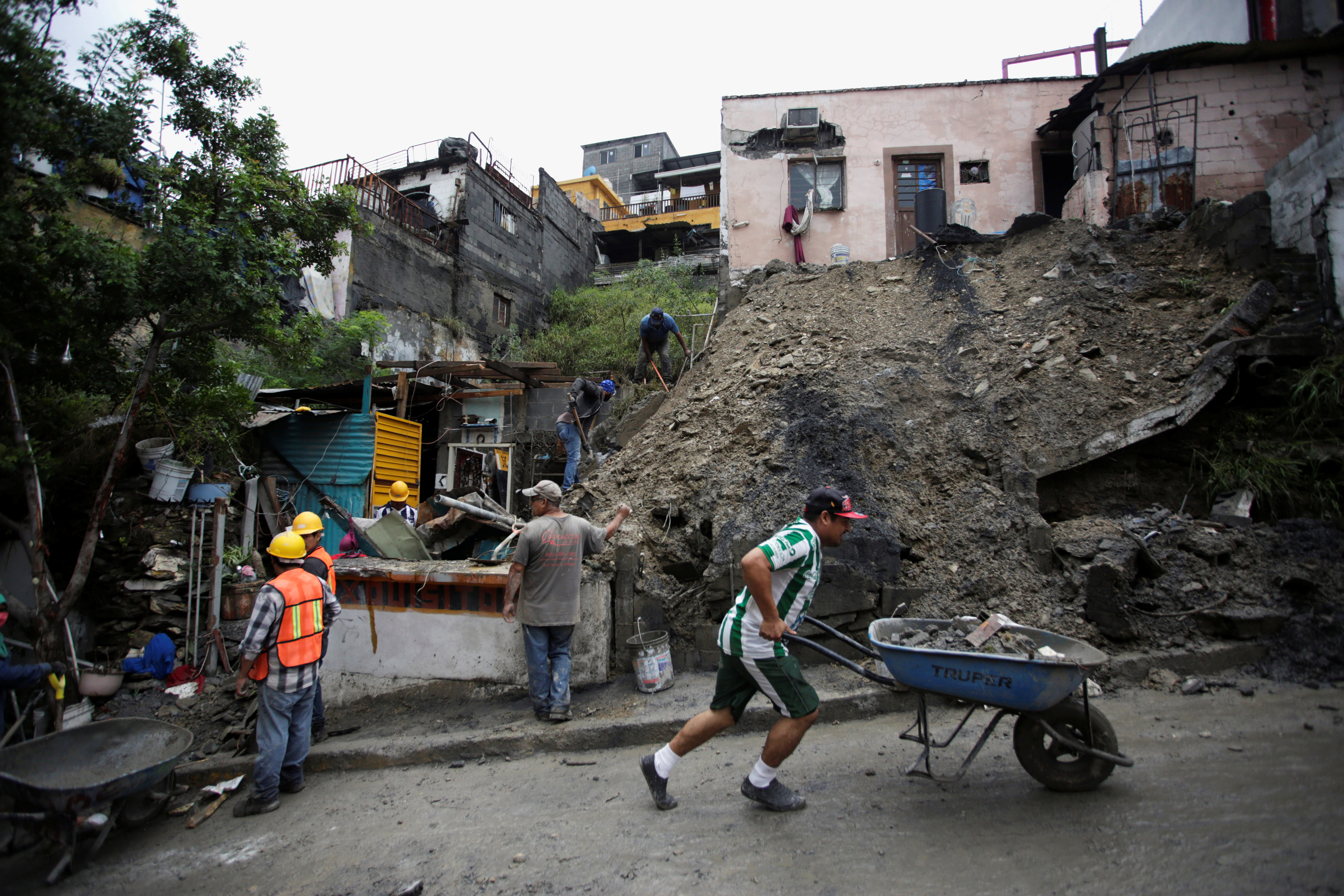 La gente trabaja para eliminar el lodo y las rocas después de un deslizamiento de tierra después de la tormenta Hanna en Monterrey, México, 27 de julio de 2020.