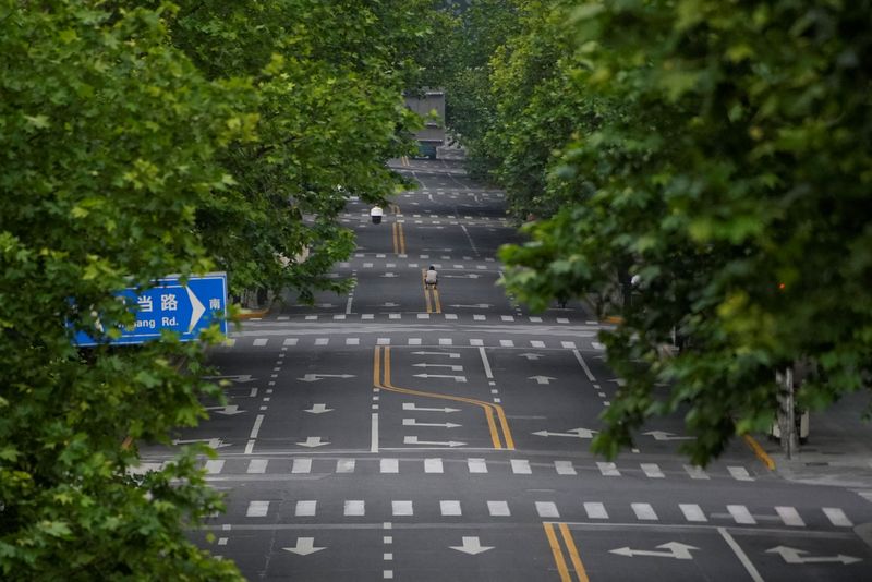 Un hombre toma una foto en una calle vacía durante el bloqueo, en medio de la pandemia de la enfermedad del coronavirus (COVID-19), en Shanghai, China, este 26 de mayo de 2022 (Reuters)