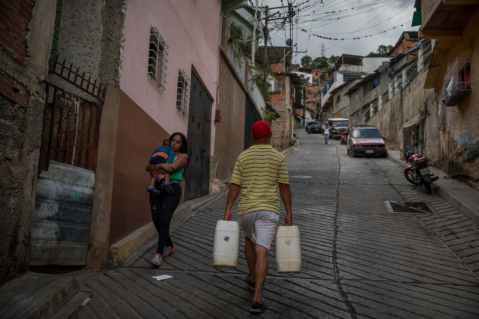 Un hombre carga dos recipientes plásticos de 25 litros de agua cada uno (EFE/ Miguel Gutiérrez)
