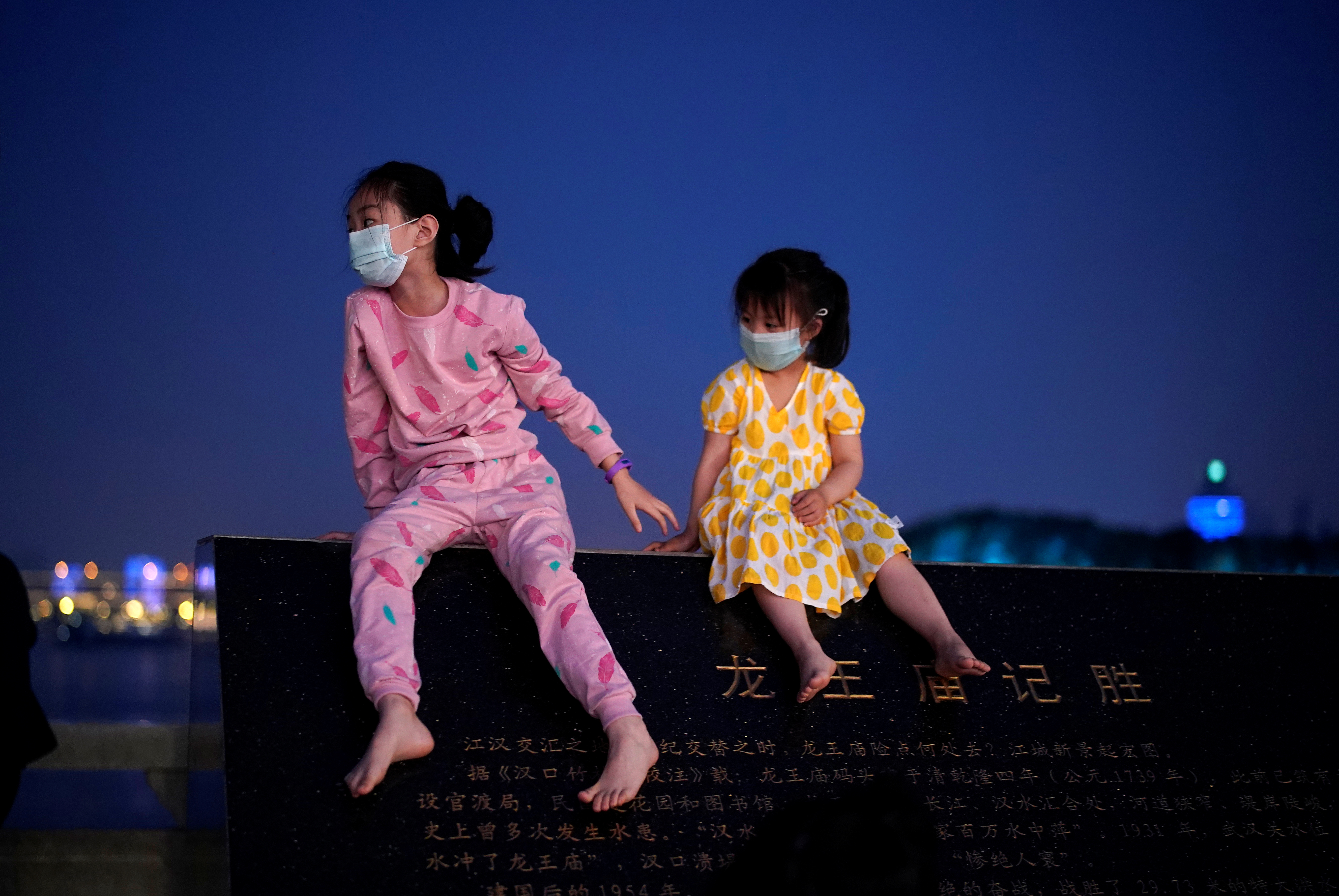 Dos nenas con sus tapabocas en Wuhan, la ciudad de China donde se disparó la pandemia. (REUTERS/Aly Song)