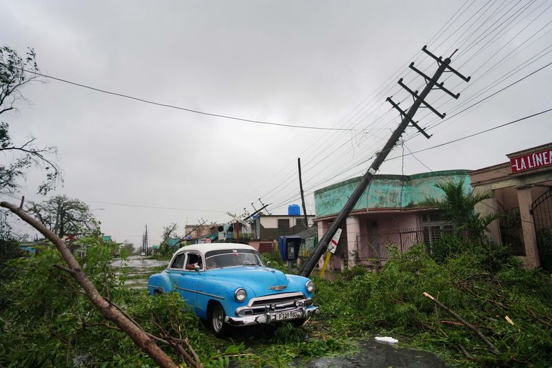 Un auto de época pasa junto a los escombros causados por el huracán Ian a su paso por Pinar del Río