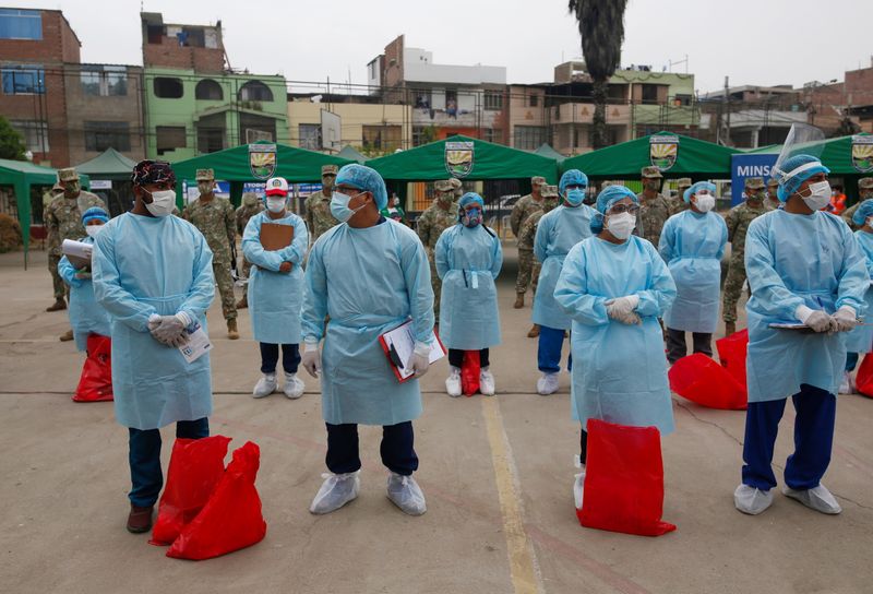 Trabajadores de la salud y soldados se ven antes de la realización de pruebas masivas por COVID-19, en Lima, Perú