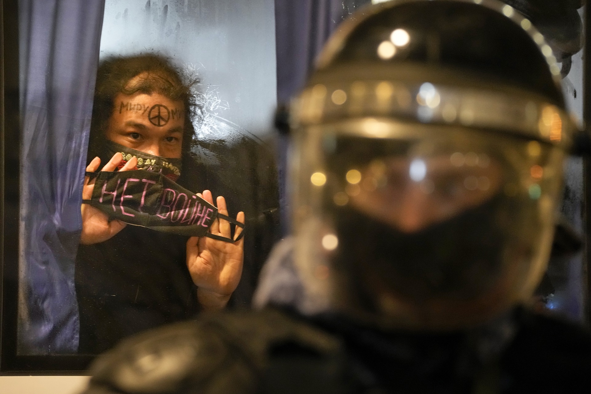 Una manifestante detenida muestra la frase "¡No a la guerra!" escrita en una mascarilla, desde un bus de la policía, en San Petersburgo (AP)