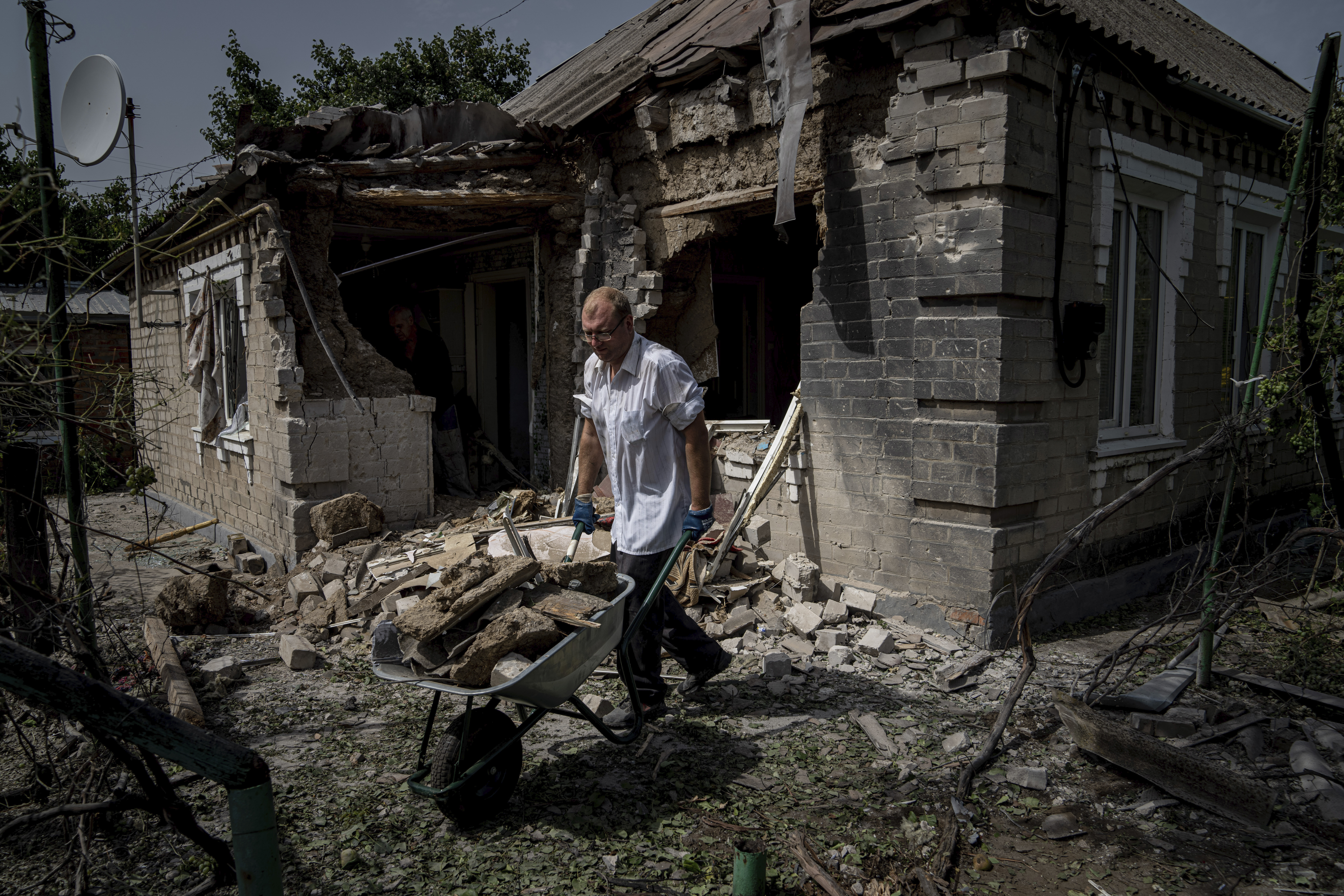 Un hombre limpia los escombros frente a la casa que resultó dañada después del bombardeo ruso de un área residencial en Nikopol, Ucrania, el lunes 22 de agosto de 2022. (AP/Evgeniy Maloletka)
