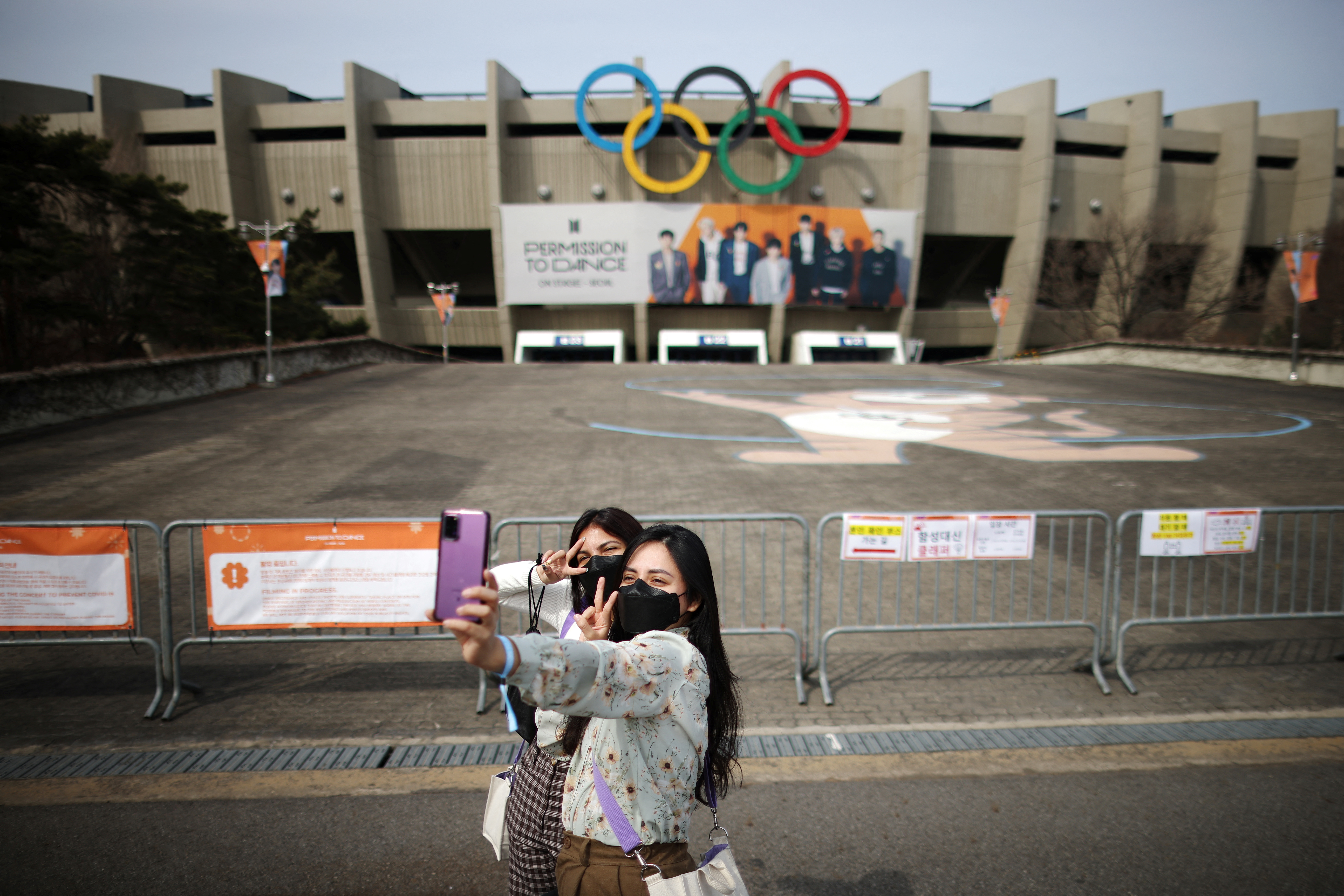Fans de la banda de K-pop BTS se toman fotografías frente al Seoul Olympic Stadium en espera de su concierto. REUTERS


