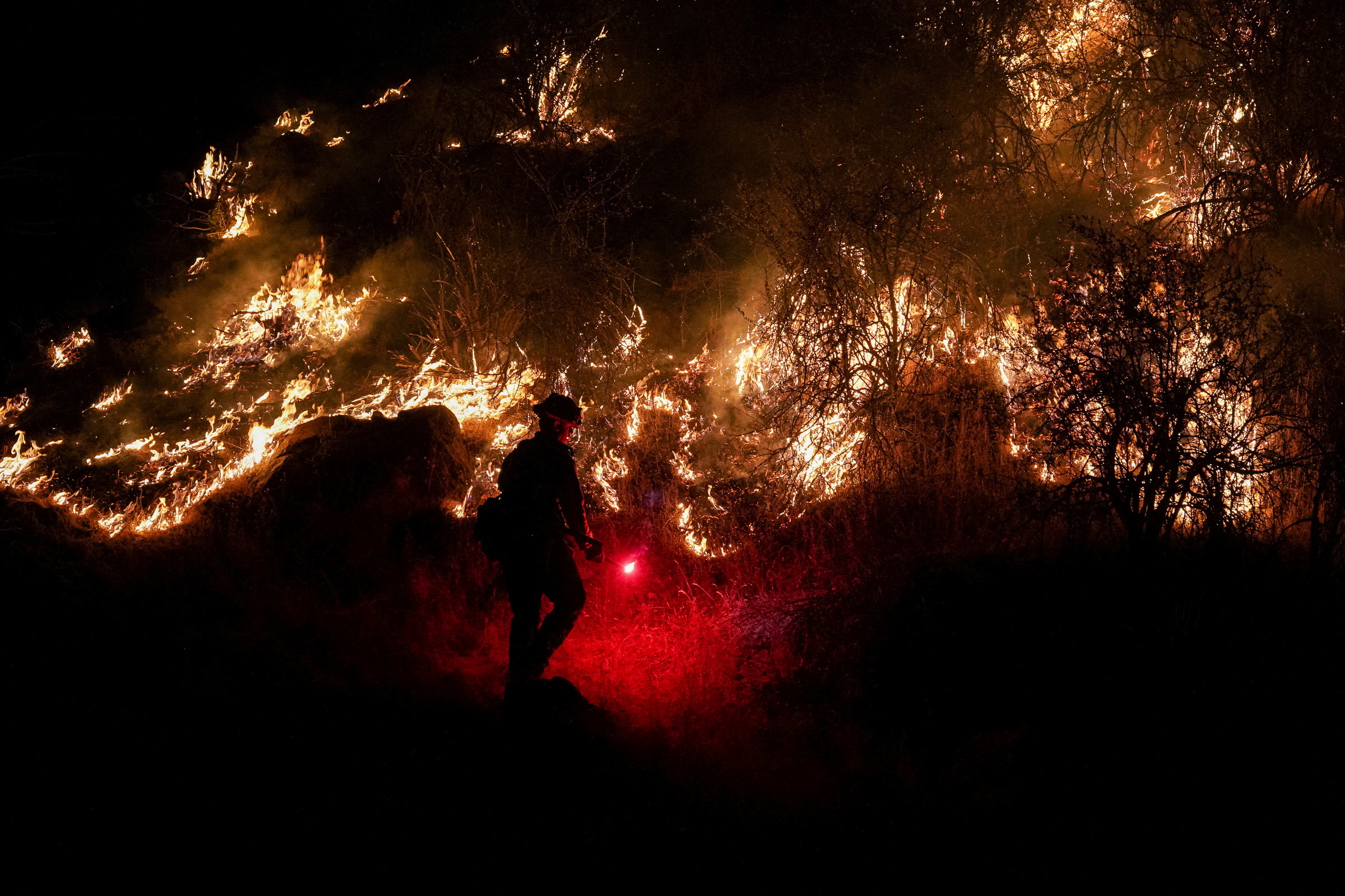 Un bombero enciende un quemador cerca de Midpines Park a lo largo de la carretera 140 mientras el Oak Fire arde cerca de Mariposa, California, el 22 de julio de 2022 (REUTERS/Tracy Barbutes)