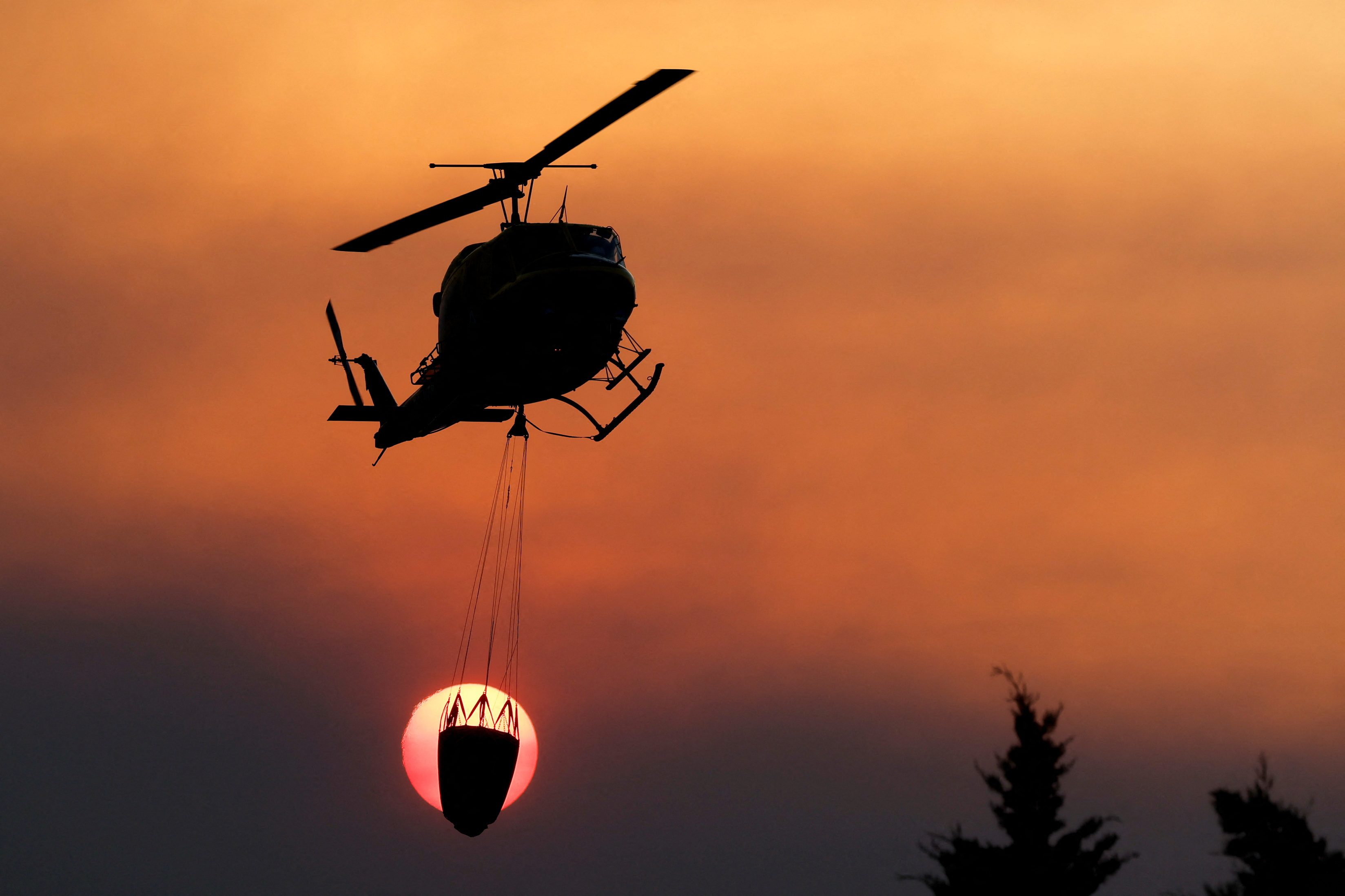 Un helicóptero rellena de agua mientras trabaja en la extinción de un incendio forestal en Alhaurín el grande, España, 15 de julio de 2022. REUTERS/Jon Nazca