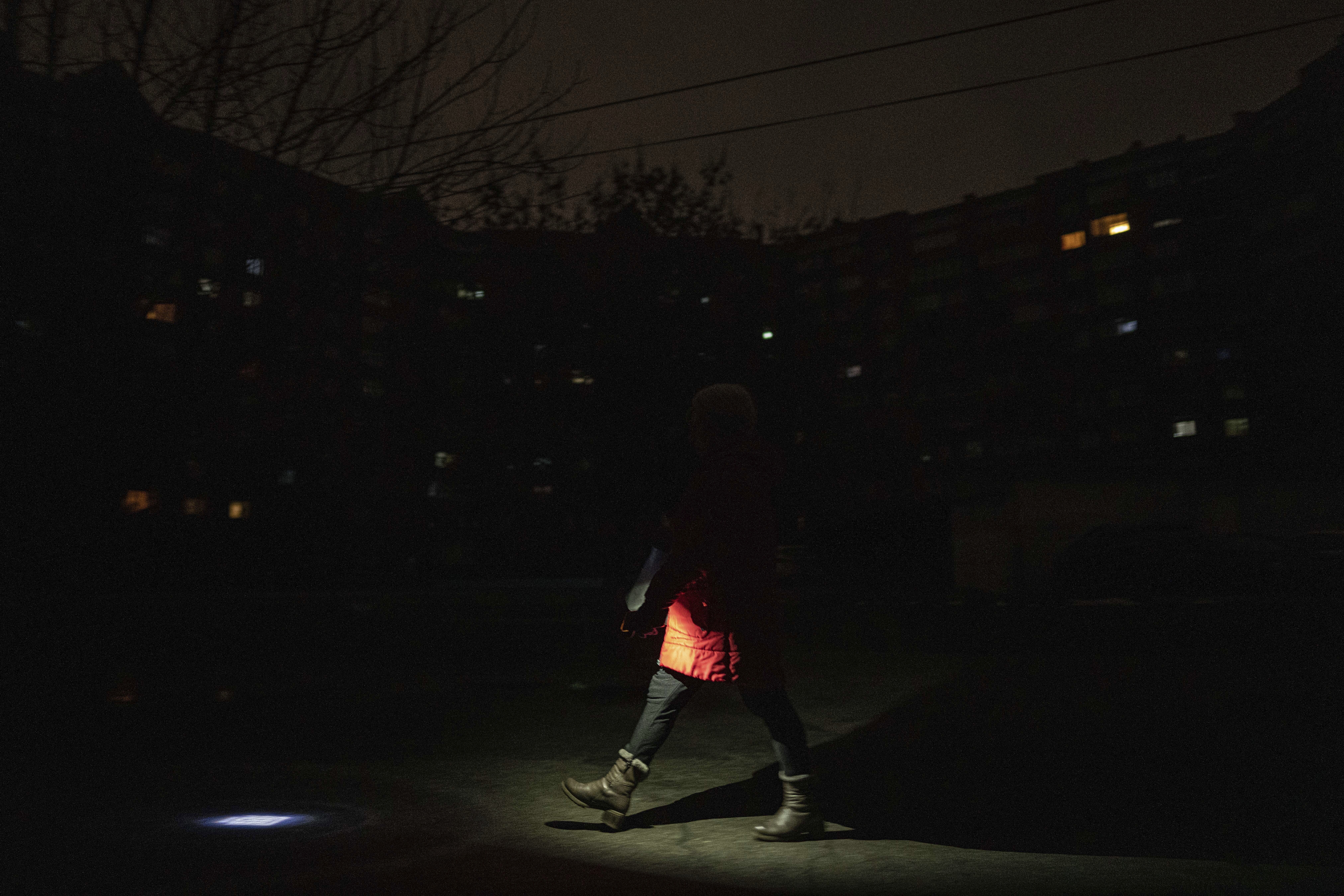 A woman illuminates the street with a flashlight during a power outage in kyiv, Ukraine, on Feb. 3, 2023. (AP Photo/Evgeniy Maloletka)
