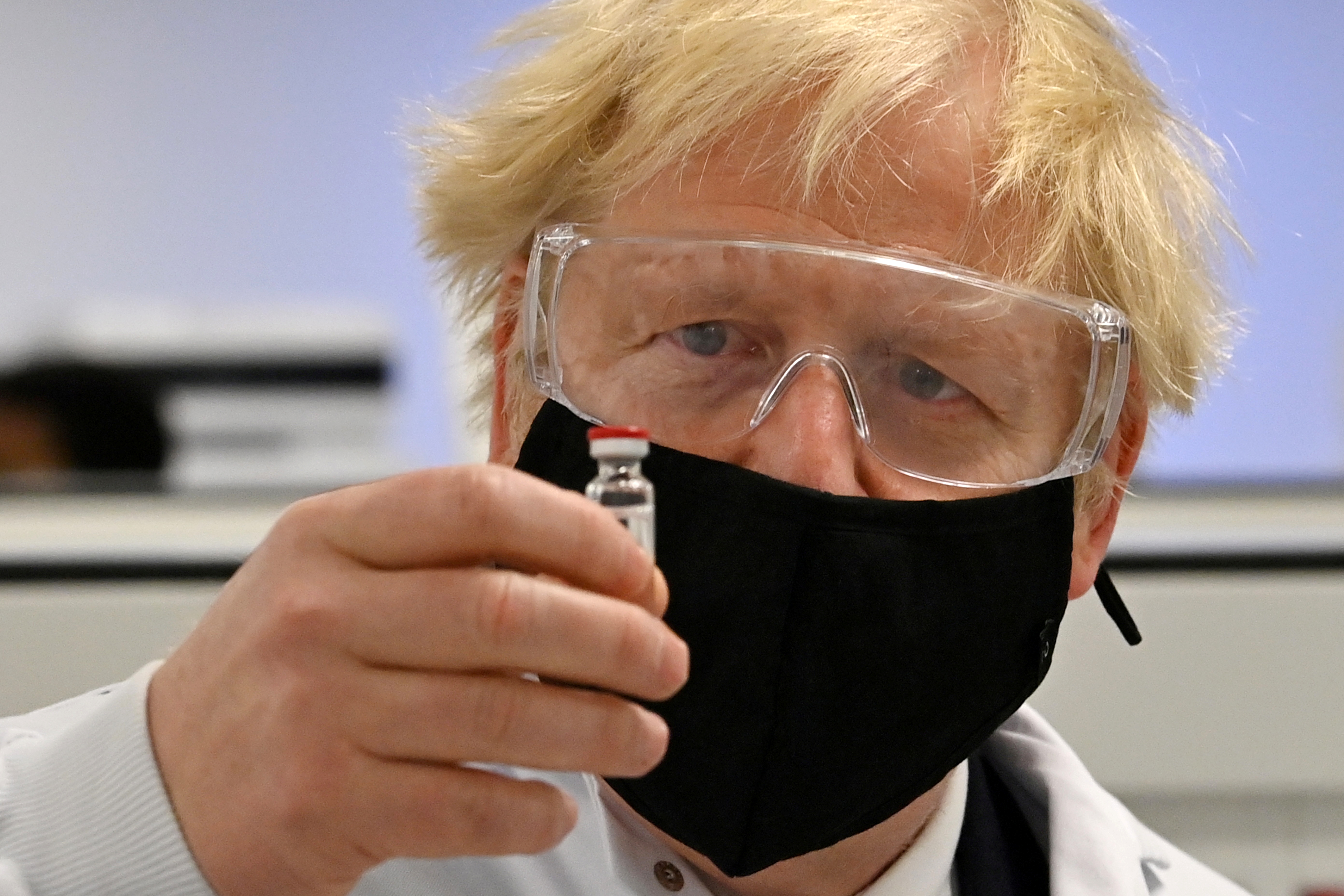El premier británico Boris Johnson observa un vial de la candidata de Oxford y Astrazeneca (Reuters)