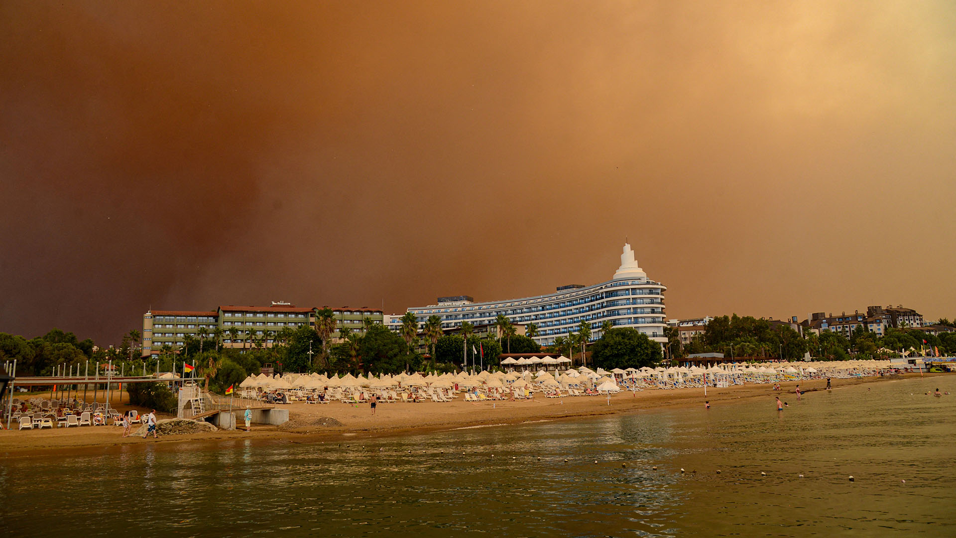 El humo oscuro se desplaza sobre un complejo hotelero durante un incendio forestal masivo que envolvió una región turística del Mediterráneo en la costa sur de Turquía cerca de la ciudad de Manavgat, el 29 de julio de 2021. (Foto de Ilyas AKENGIN / AFP)
