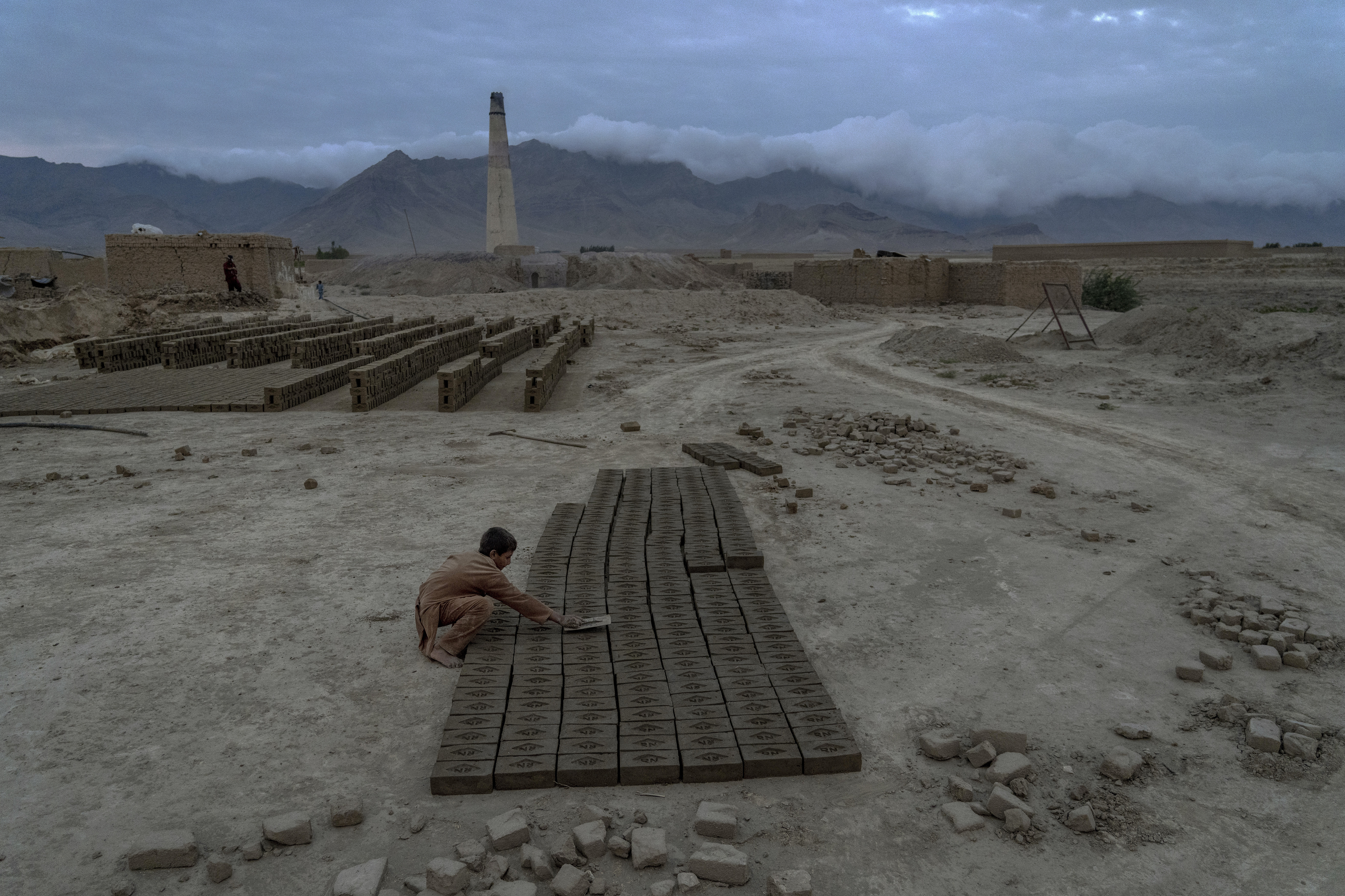 An 8-year-old boy arranges the bricks to dry.
