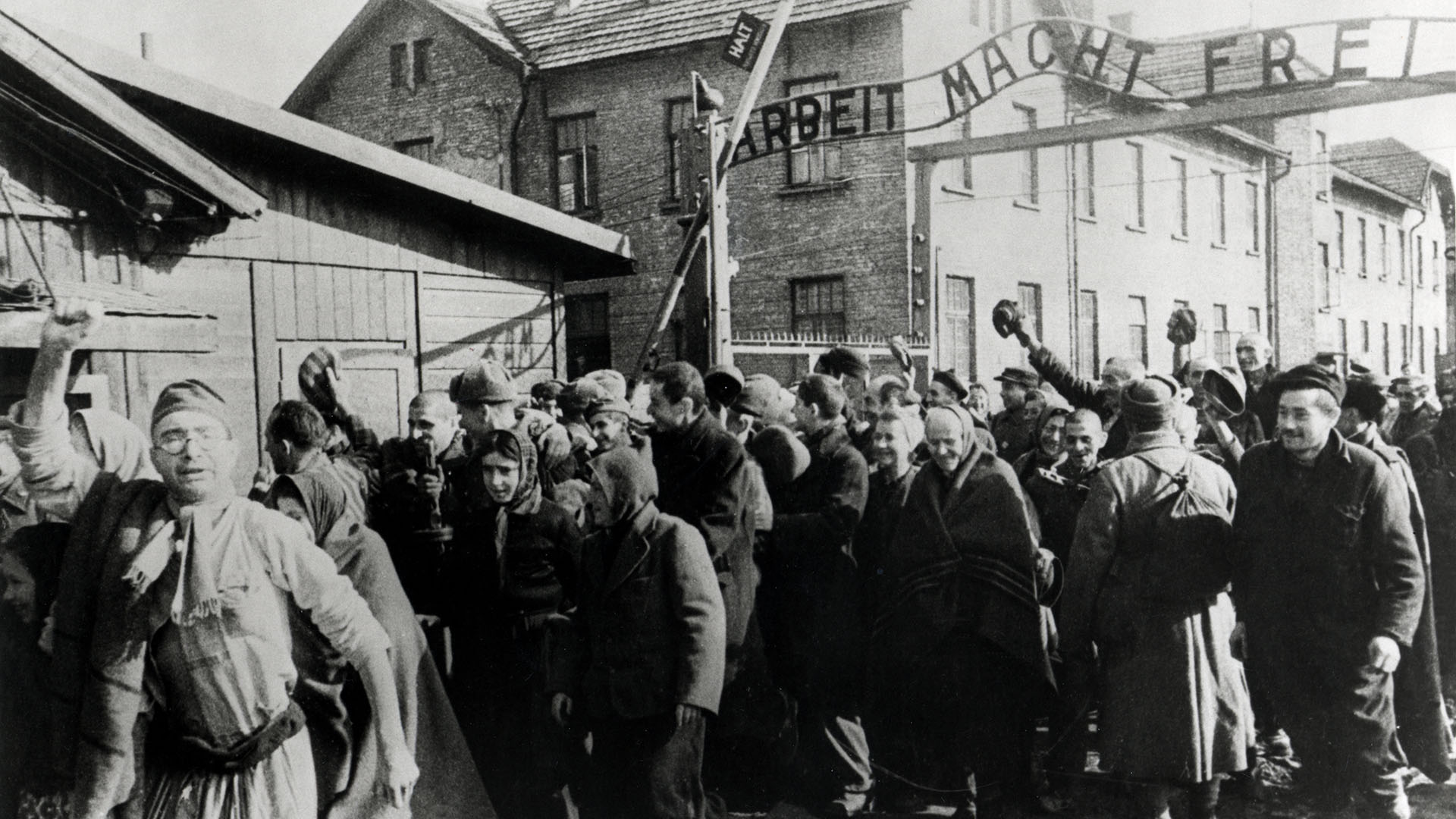 La imagen fue tomada por un fotógrafo ruso: sobrevivientes de Auschwitz salen del campo al final de la Segunda Guerra Mundial en febrero de 1945. Sobre ellos está el eslogan alemán "Arbeit macht frei" ("El trabajo hace libre") (Galerie Bilderwelt/Getty Images)