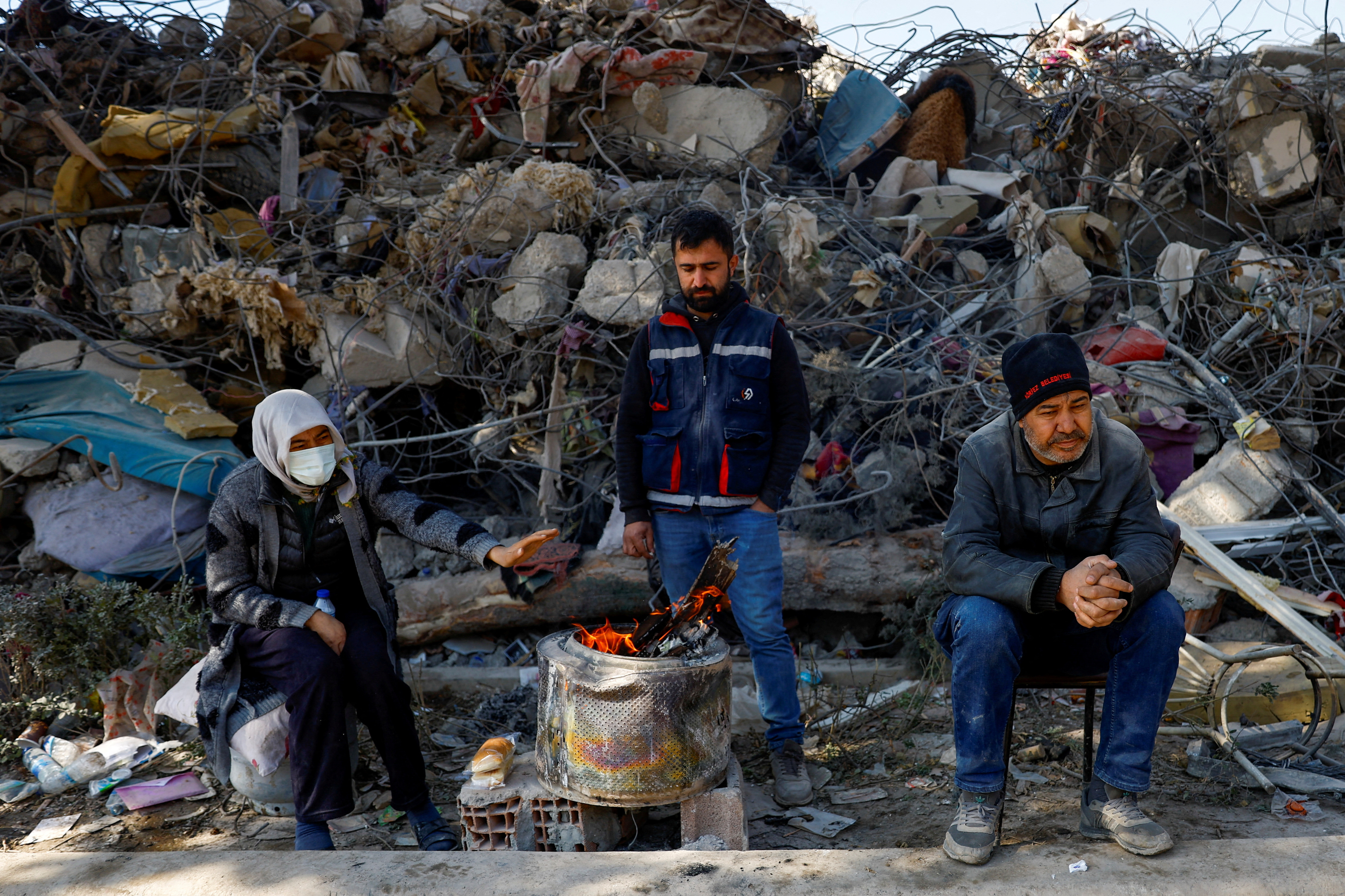 La gente se mantiene caliente junto a un fuego cerca de los escombros, tras el terremoto mortal en Kahramanmaras, Turquía 14 de febrero 2023. REUTERS/Suhaib Salem