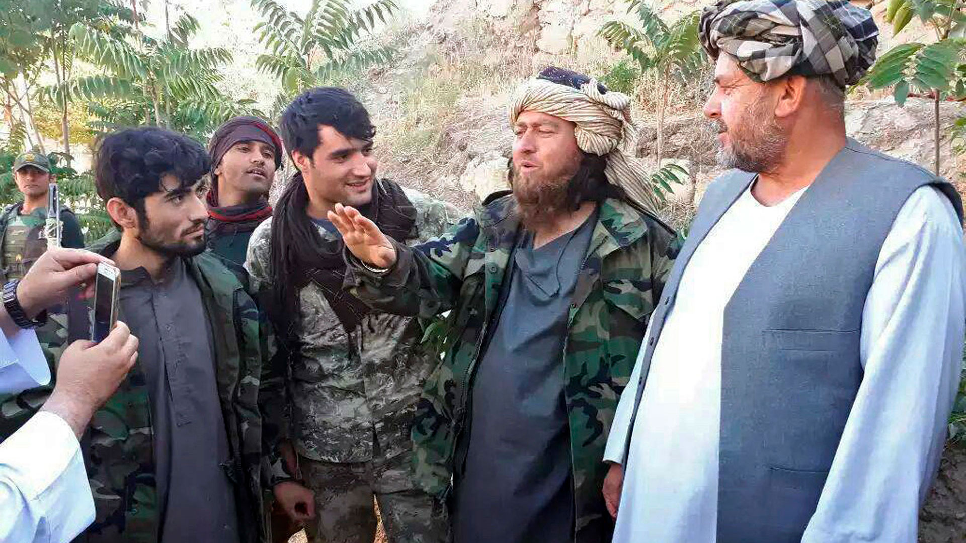 Un combatiente extranjero del grupo Estado Islámico, segundo a la derecha, habla con un periodista después de que se rindiera a las fuerzas de seguridad del gobierno en el distrito de Darzab de la provincia de Jawzjan, al norte de Kabul, Afganistán, el miércoles 1 de agosto de 2018. (Foto AP)
