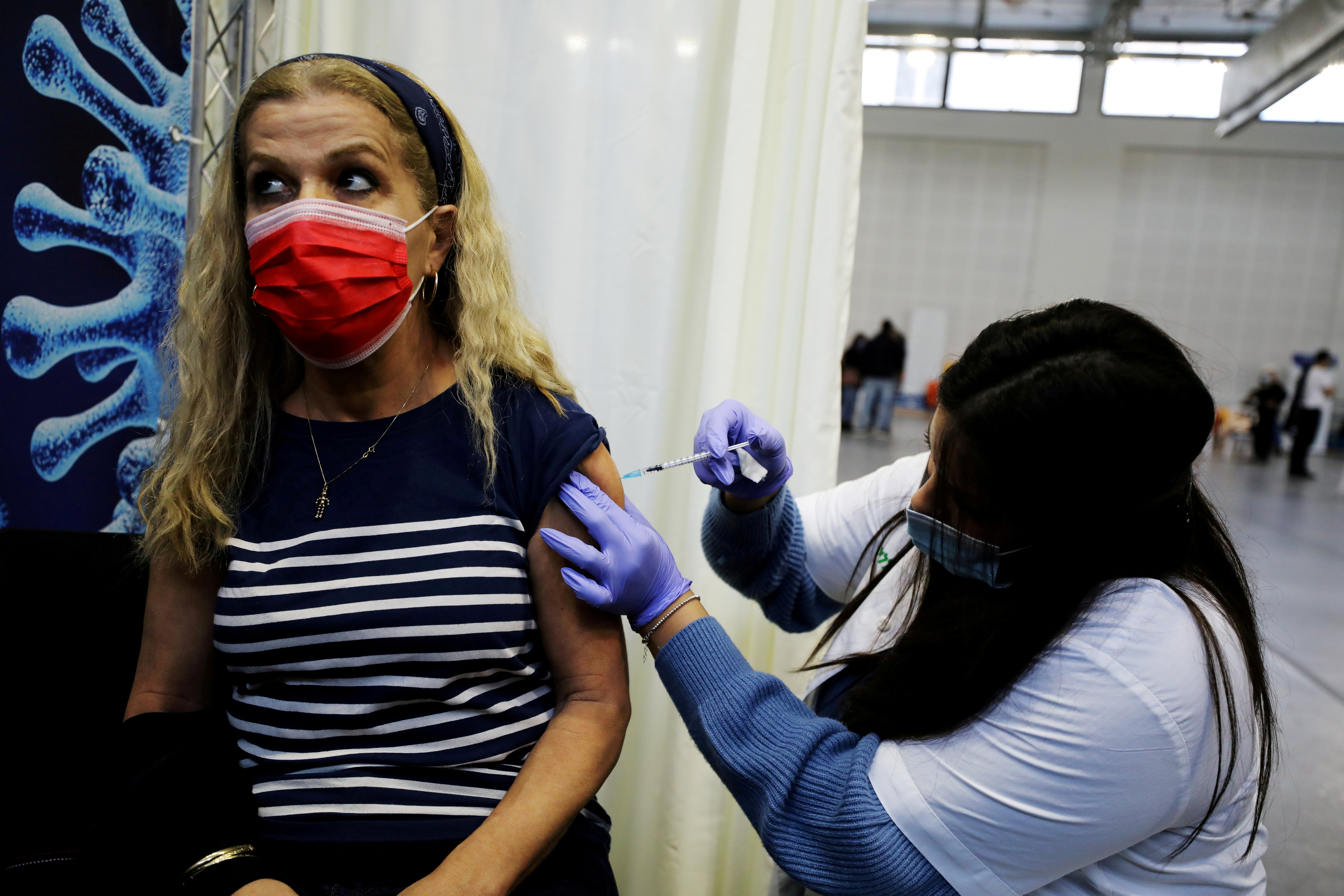 FOTO DE ARCHIVO: Una mujer recibe una vacuna contra la enfermedad del coronavirus (COVID-19) en un centro temporal de la organización de mantenimiento de la salud (HMO) Clalit, en una cancha de baloncesto en Petah Tikva, Israel, el 28 de enero de 2021. REUTERS / Ammar Awad