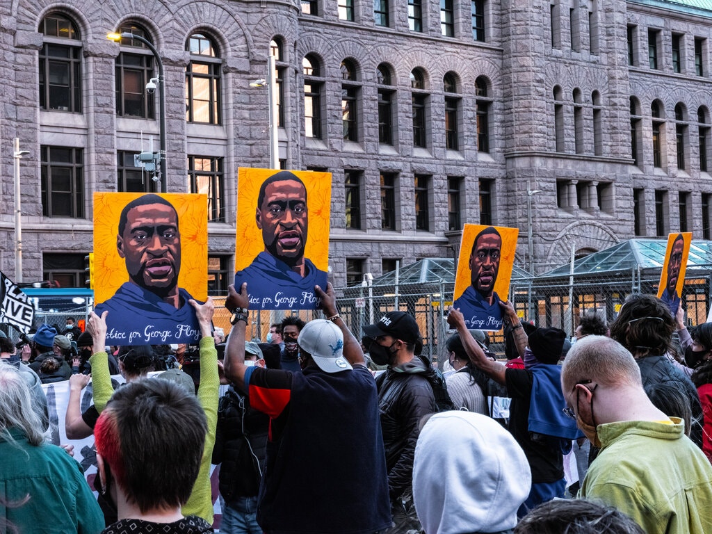 Manifestantes sostienen retratos de George Floyd mientras cientos de personas se reúnen fuera del edificio de la corte en Minneapolis, el lunes 29 de marzo de 2021, para un mitin al final del primer día del juicio contra el expolicía Derek Chauvin. (Joshua Rashaad McFadden/The New York Times).