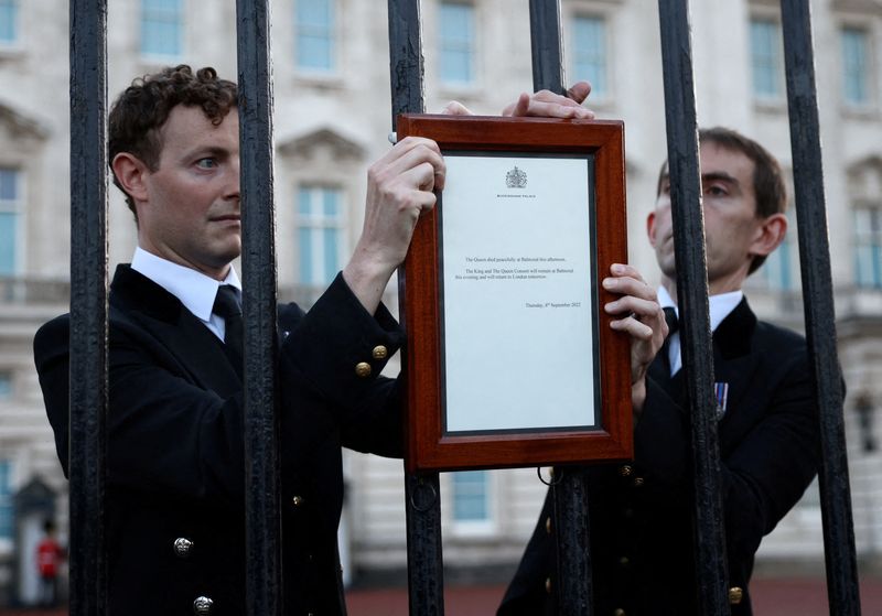 El Personal coloca un cartel anunciando la muerte de la Reina Isabel en una valla fuera del Palacio de Buckingham