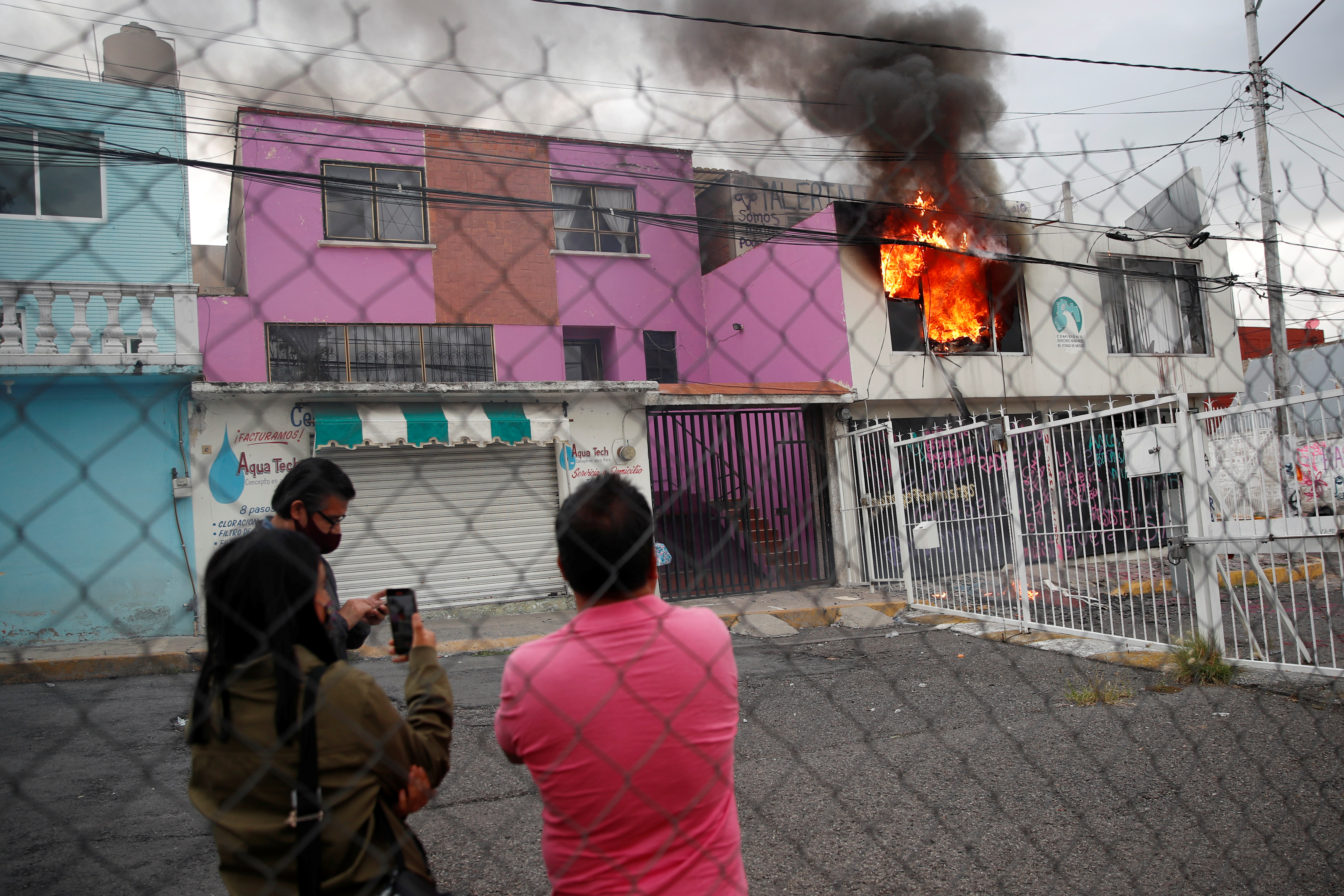 La gente observa un incendio que estalló luego de que miembros de un colectivo feminista destrozaran las instalaciones de la comisión de derechos humanos del estado de México, en apoyo a víctimas de violencia de género, en Ecatepec, Estado de México, México el 11 de septiembre de 2020.