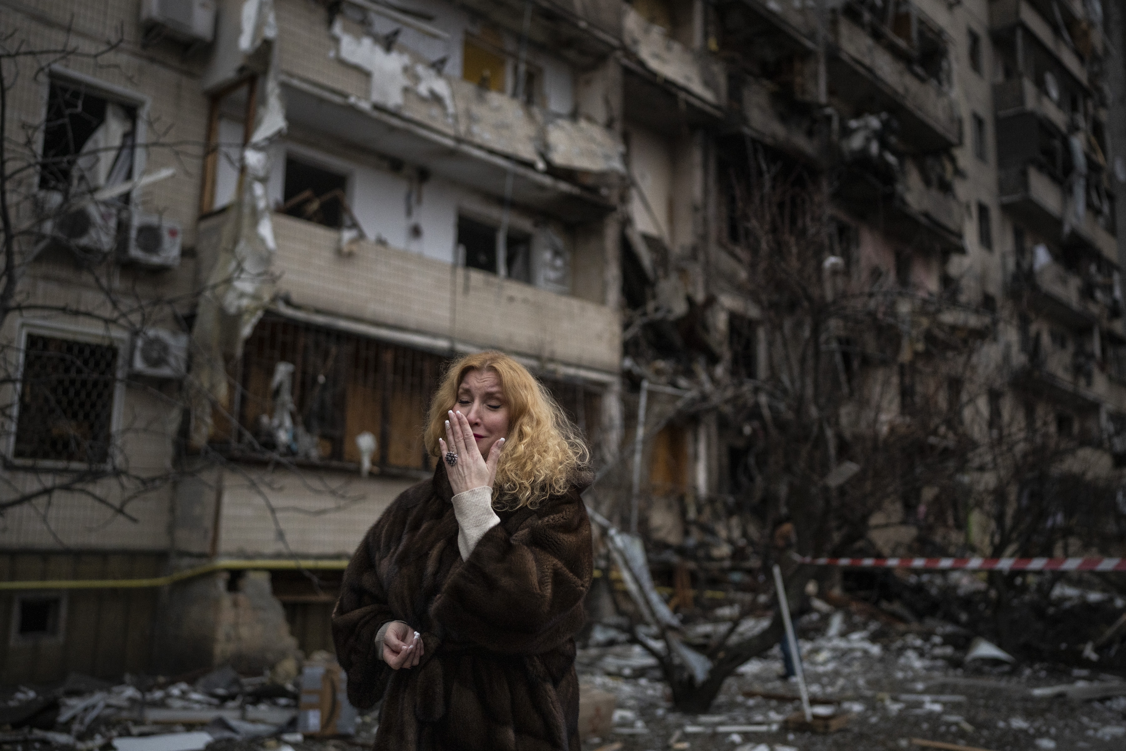 Natali Sevriukova llora frente a su edificio de apartamentos destruido en un ataque con cohetes en Kiev, Ucrania, el 25 de febrero de 2022 (Foto AP/Emilio Morenatti)
