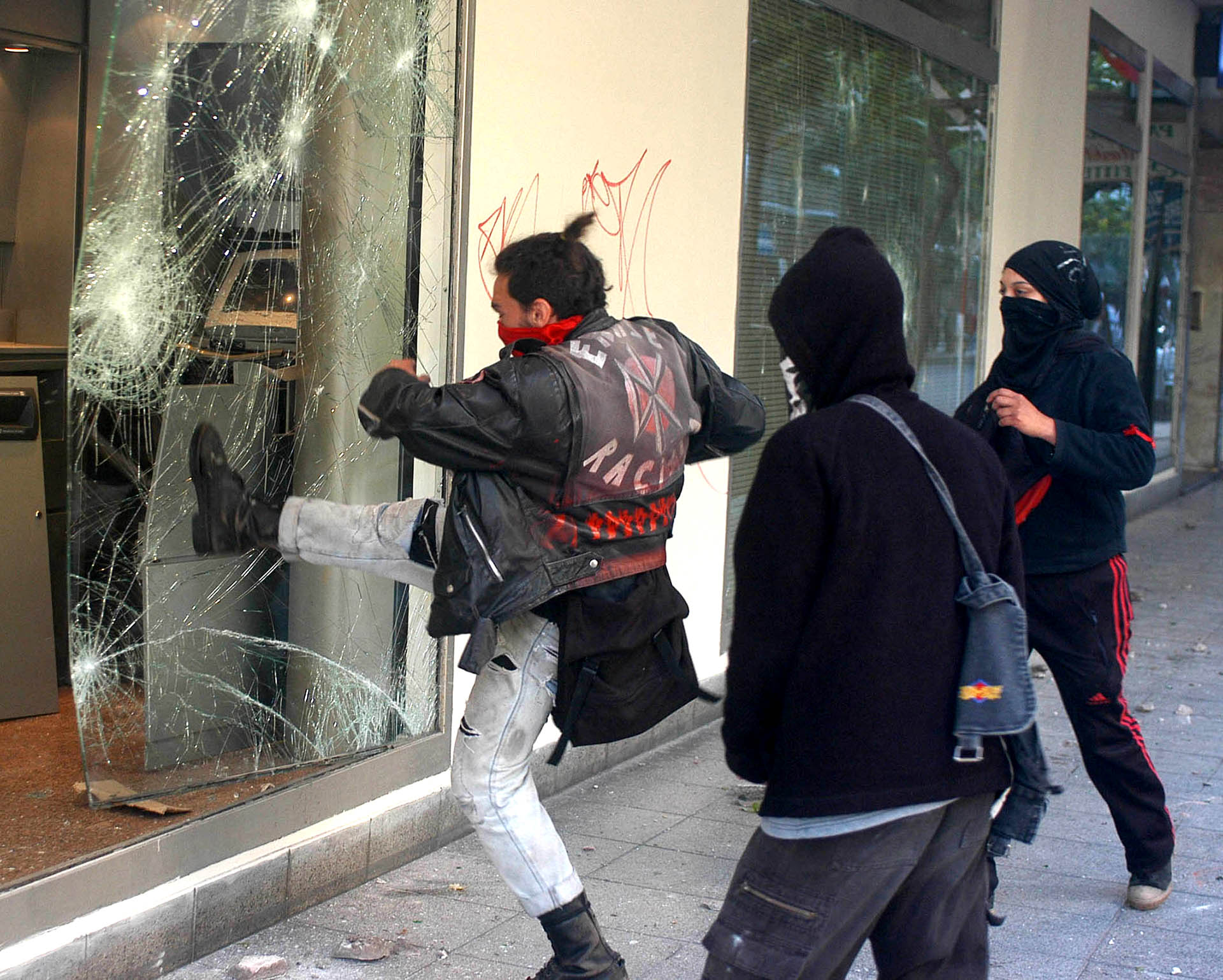 Un manifestante rompe una vidriera durante los incidentes que se produjeron en la avenida Colón