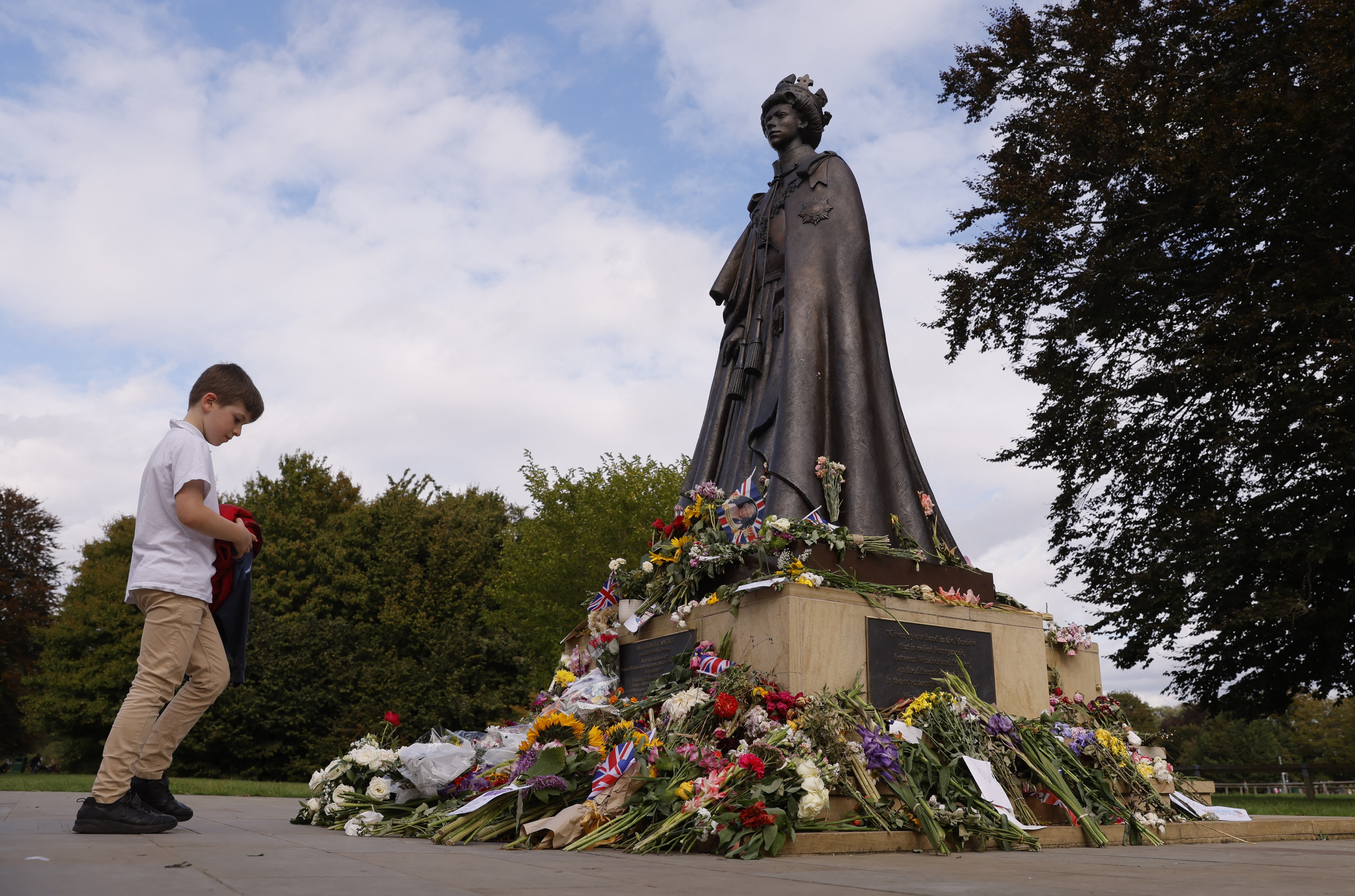 Las flores y los mensajes se colocan junto a una estatua de la reina Isabel de Gran Bretaña. 