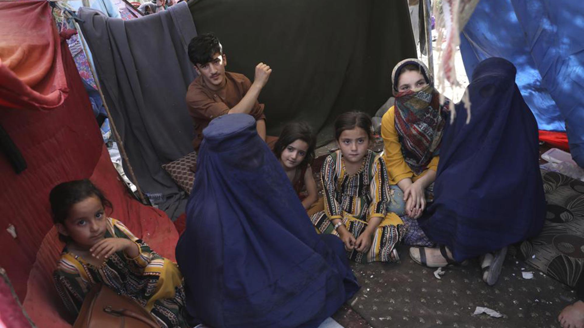 Una maestra desplazada internamente que lleva un burka de la provincia de Takhar, que se identificó con su nombre de pila, Nilofar, a la izquierda, habla durante una entrevista con The Associated Press dentro de su tienda de campaña en un parque público en Kabul, Afganistán (AP)