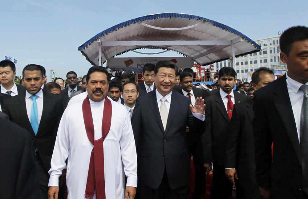 ARCHIVO - El presidente Mahinda Rajapaksa, de blanco, camina con el jefe del régimen chino Xi Jinping tras el lanzamiento oficial de un proyecto de construcción de una ciudad portuaria de 1.400 millones de dólares que se está construyendo en una isla artificial frente a Colombo, Sri Lanka, el 17 de septiembre de 2014 (AP Photo/Eranga Jayawardena)