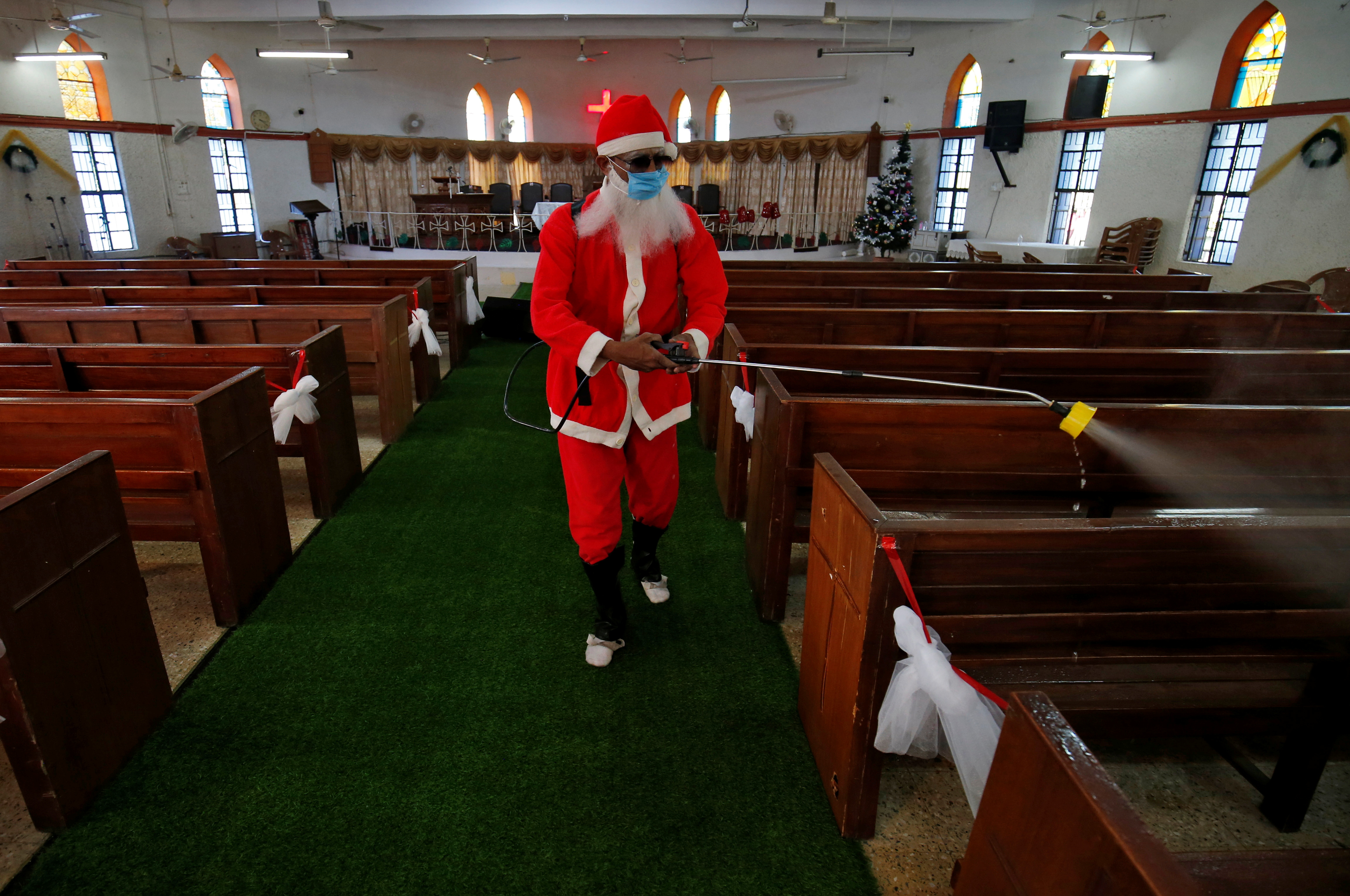 Un hombre vestido con un traje de Papá Noel higieniza el interior de una iglesia antes de las celebraciones de Navidad en Ahmedabad, India  (REUTERS/Amit Dave)