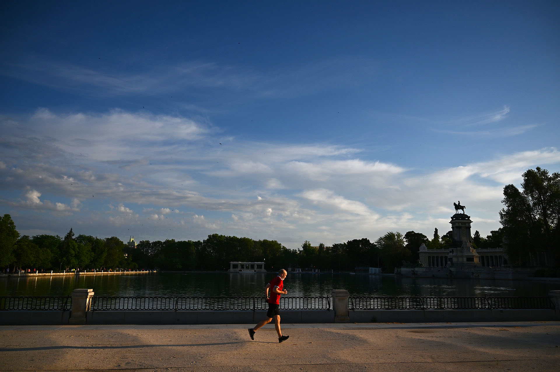 Un hombre corre en el parque de El Retiro. Los restaurantes pueden reabrir, limitando el número de clientes, y las salidas para los paseos o para practicar deporte ya no se limitan a ciertas horas del día. (Gabriel BOUYS / AFP)
