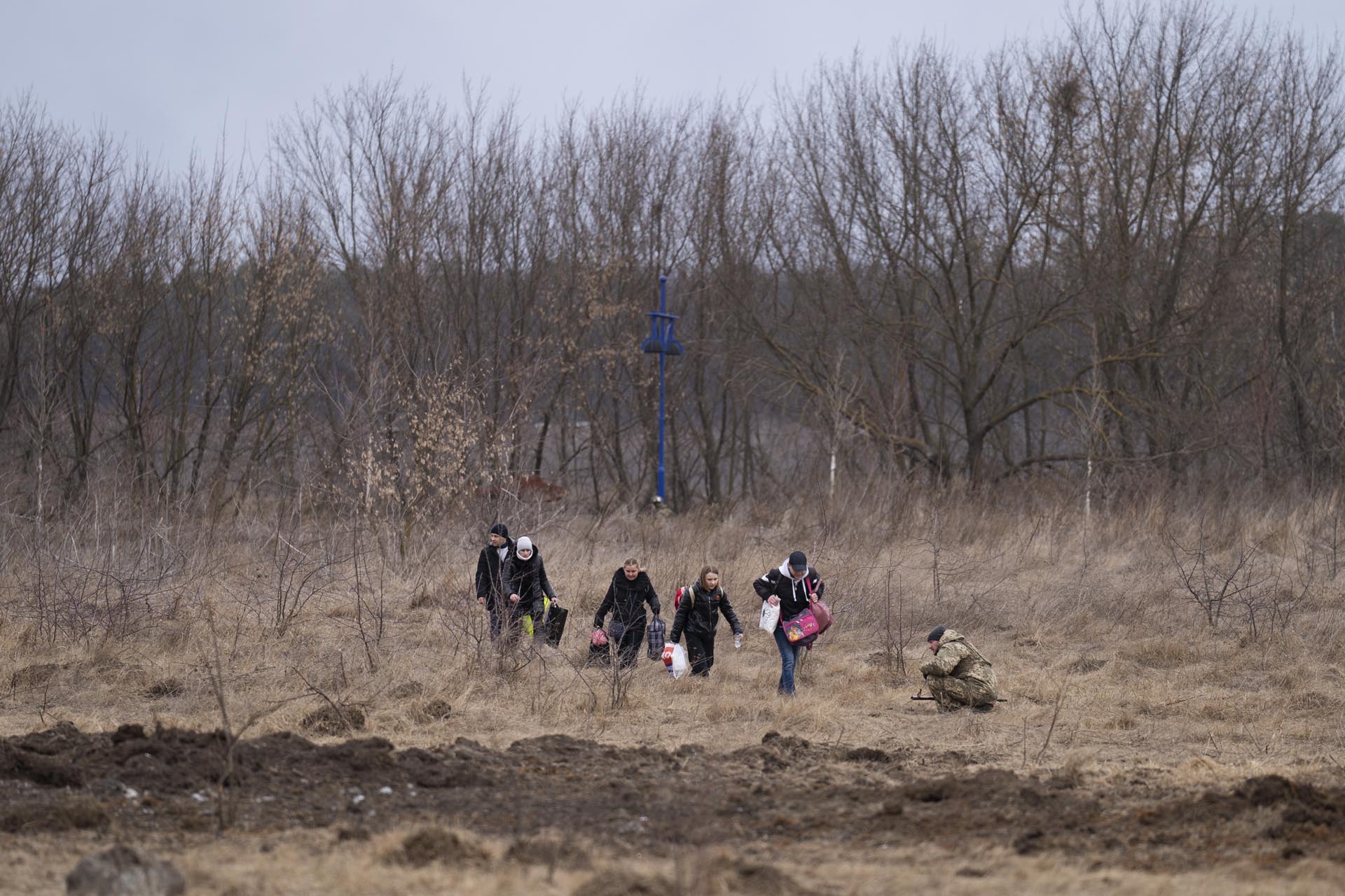 Mientras el ruido de la artillería suena cerca, un soldado ucraniano se agacha y varias personas huyen de Irpin, a las afueras de Kiev, Ucrania, el lunes 7 de marzo de 2022. 