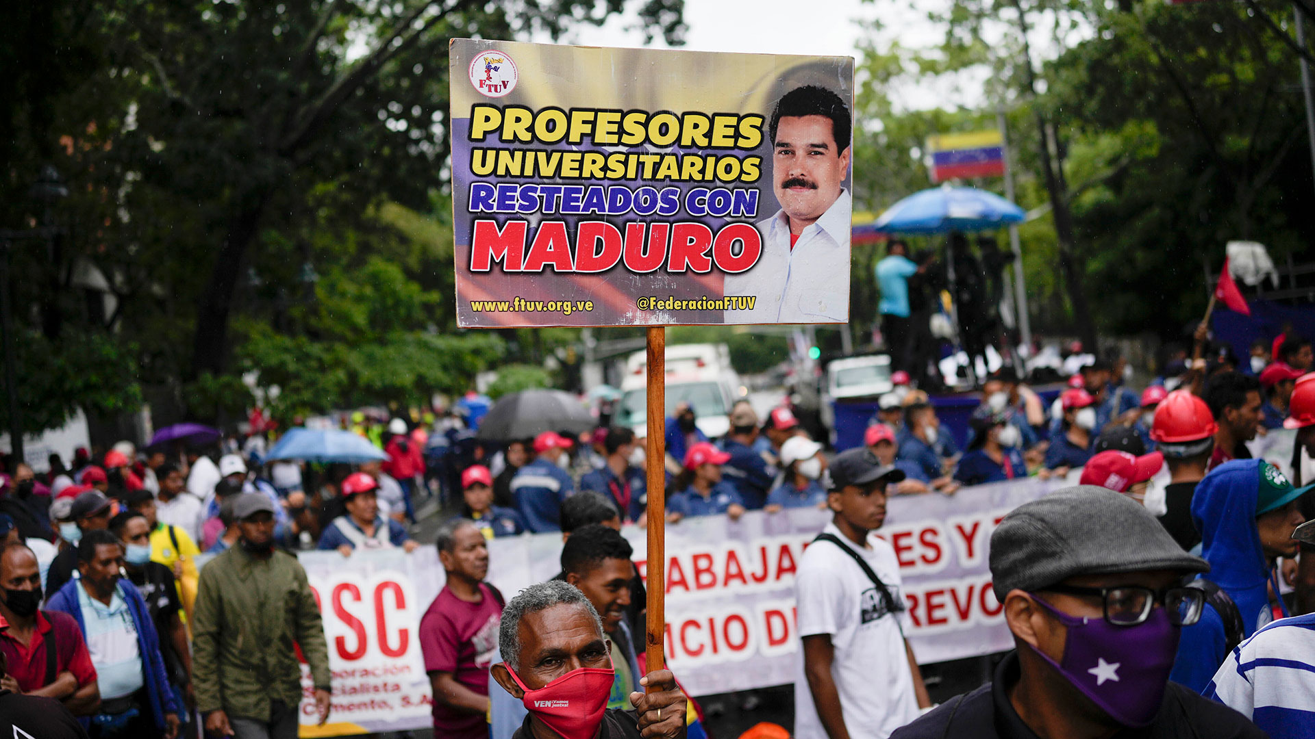 Un maestro sostiene un cartel durante una protesta de trabajadores públicos que exigen que el gobierno pague todos sus beneficios y respete los convenios colectivos en Caracas (AP Foto/Matias Delacroix)