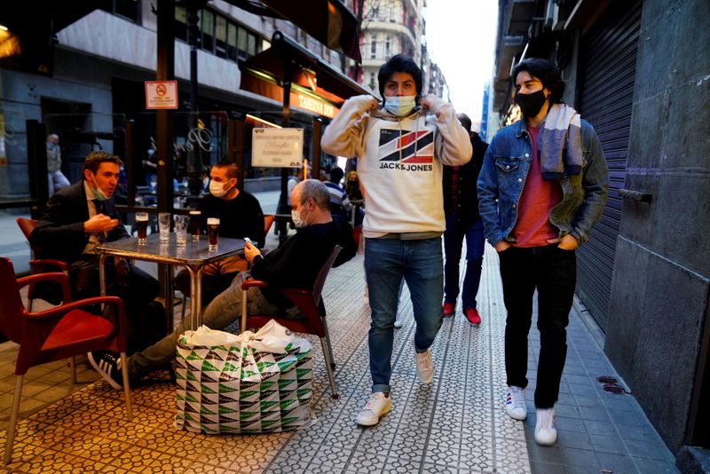 Personas con mascarilla pasan junto a los clientes de un bar después de que los bares reabrieran en el País Vasco español, en medio del brote de la enfermedad del coronavirus (COVID-19), en Bilbao, España, 19 de febrero de 2021. REUTERS/Vincent West