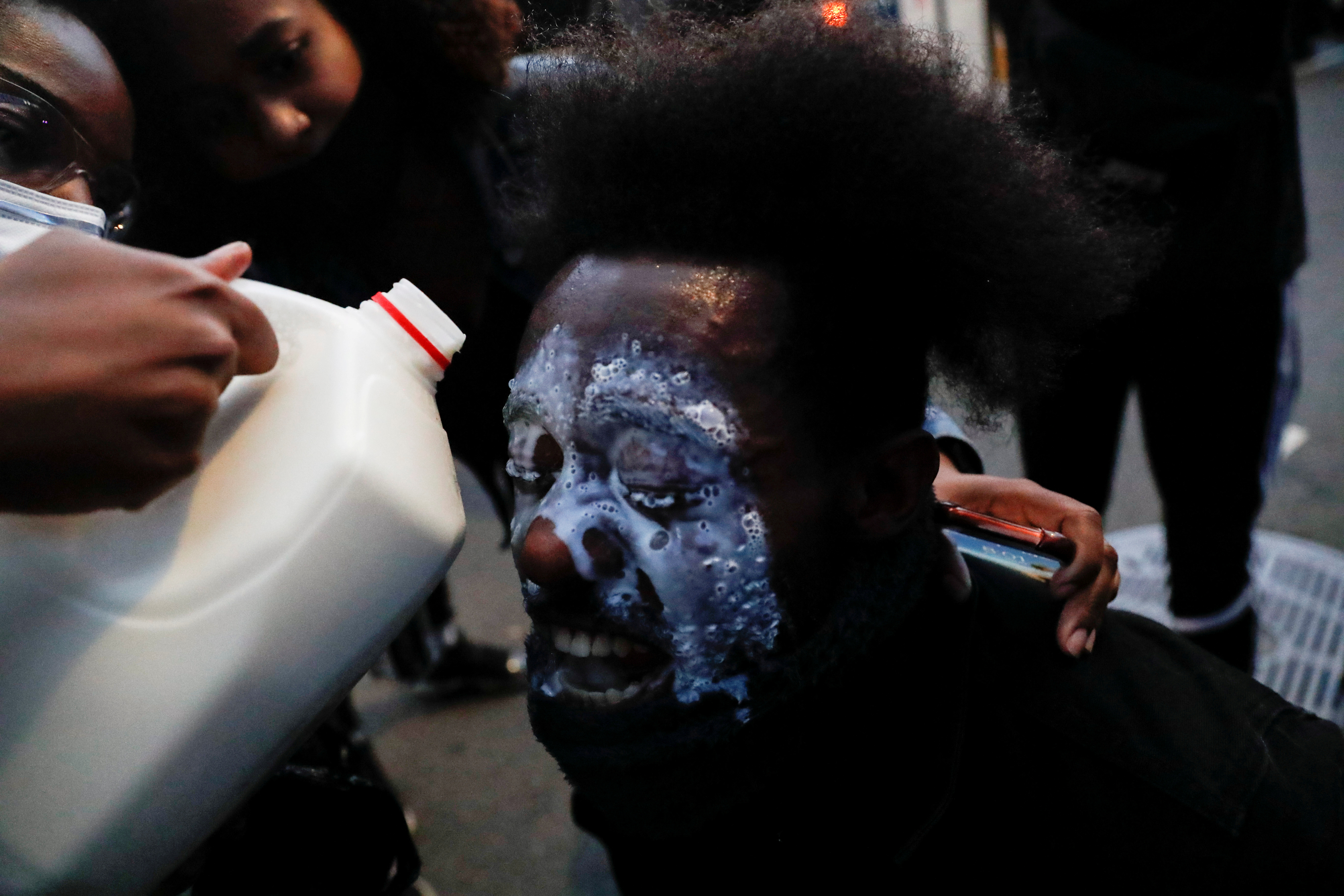 Un manifestante cuyos ojos han sido afectados por el gas lacrimógeno recibe un chorro de leche para tratar de mitigar el ardor en Brooklyn (REUTERS/Shannon Stapleton)