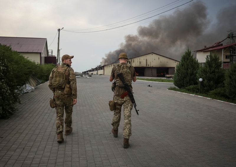 Militares ucranianos caminan mientras arden semillas en un silo de grano tras ser bombardeado repetidamente, en medio de la invasión rusa de Ucrania, en la región de Donetsk, Ucrania 31 de mayo de 2022.  REUTERS/Serhii Nuzhnenko